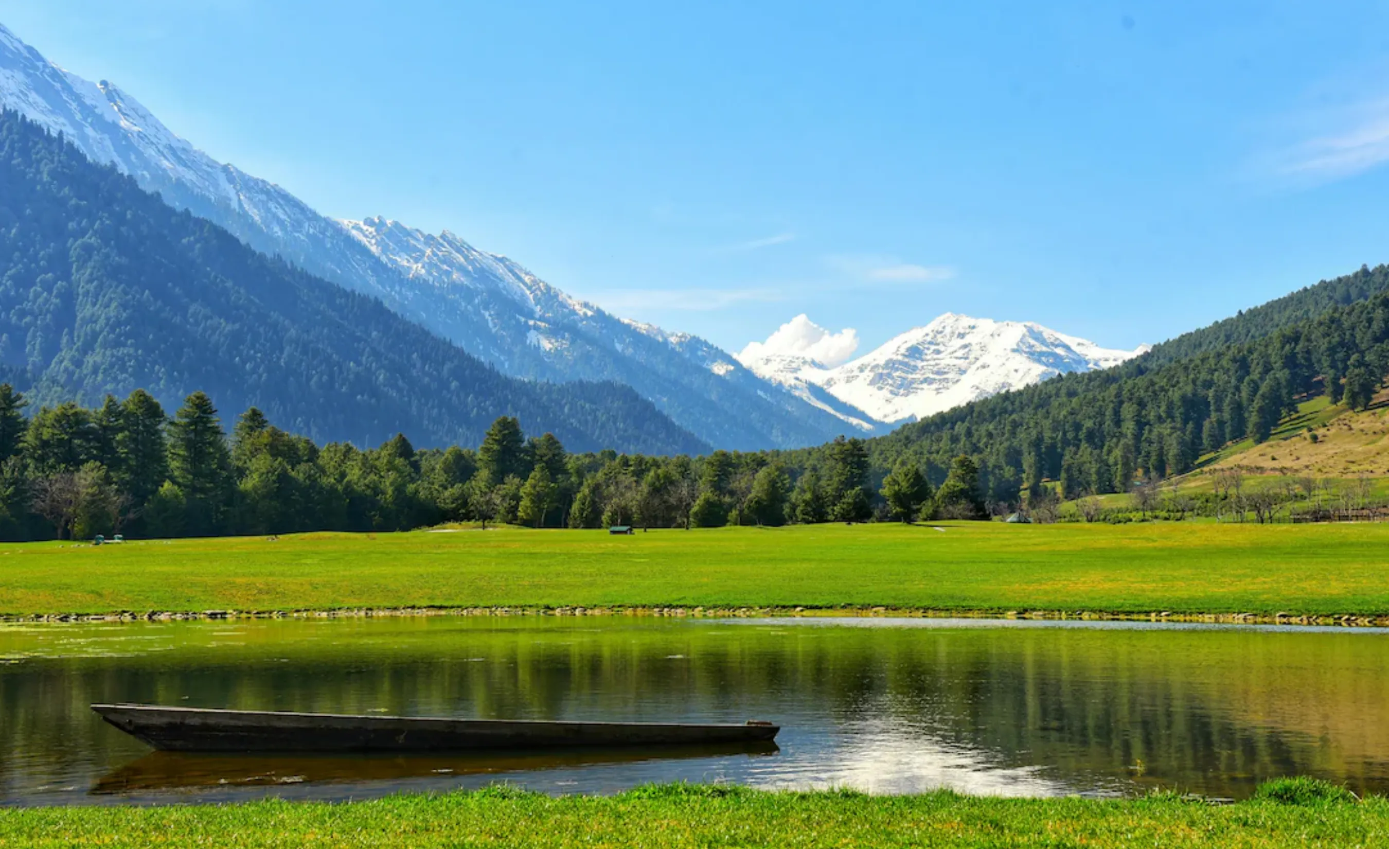 Aerial-style view of the sprawling Pahalgam valley in Kashmir, showing a river, local settlements, and a backdrop of the Himalayas.