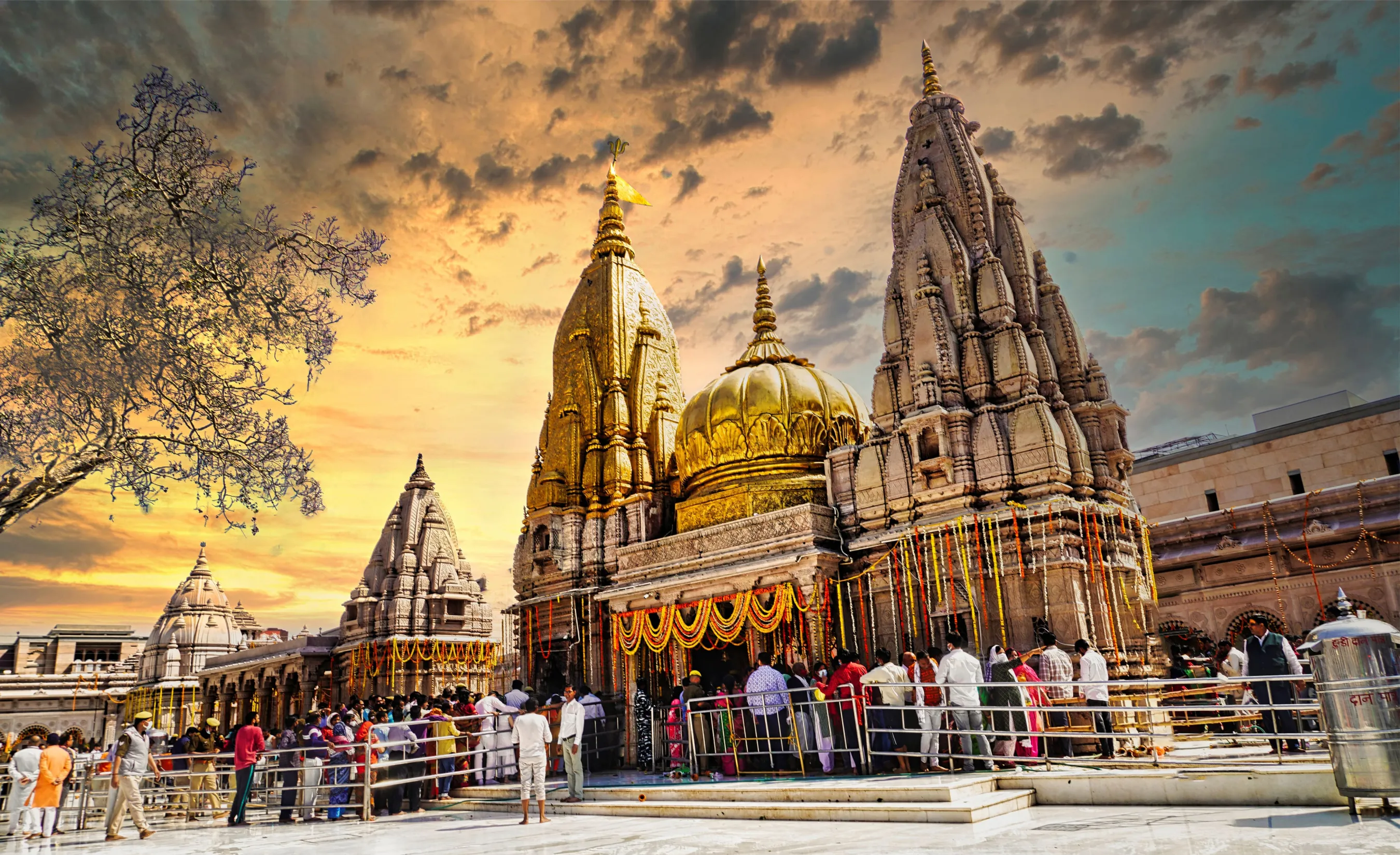 Panoramic view of the colorful heritage buildings and stone ghats along the Ganges River in Varanasi at sunset with boats.
