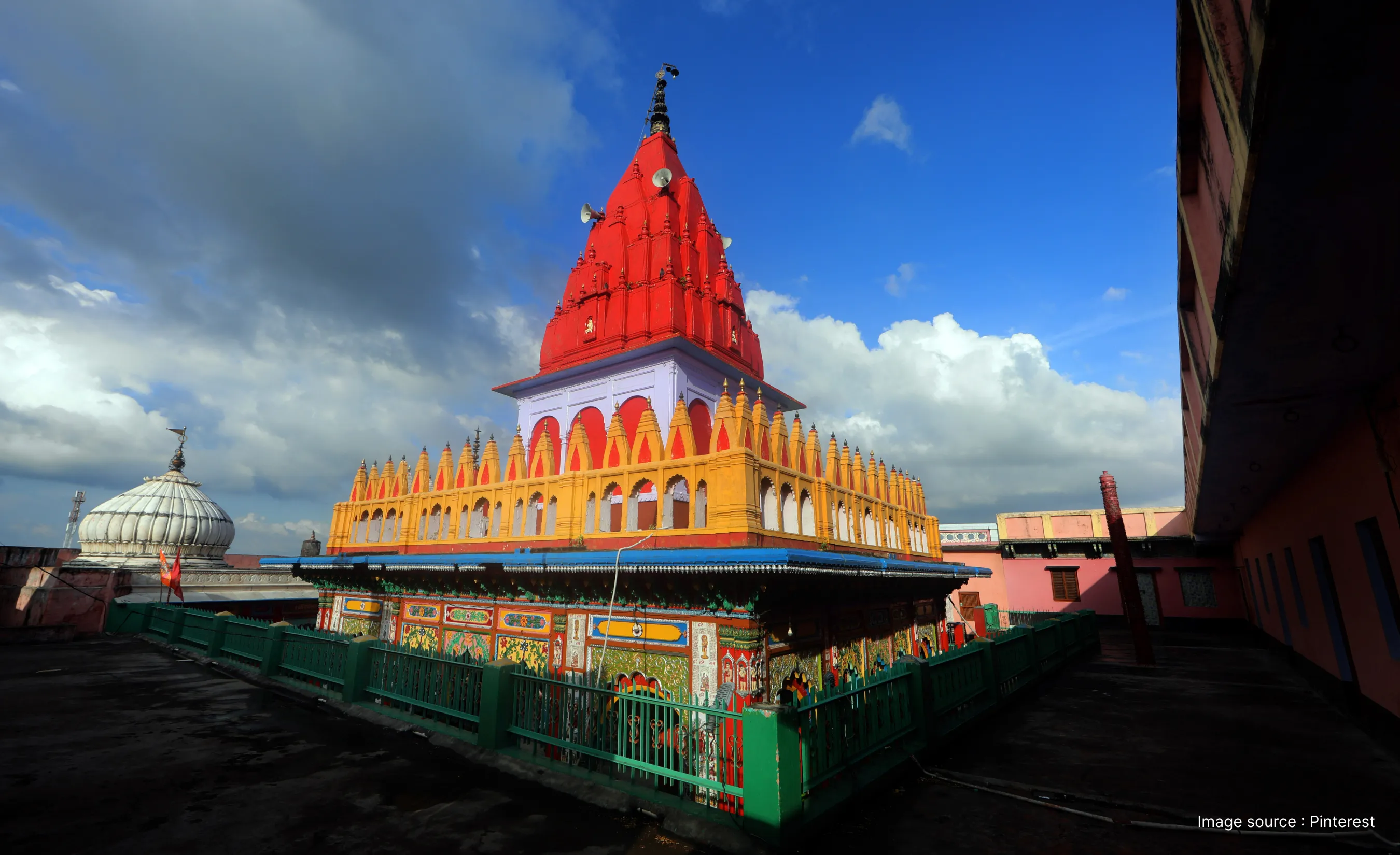 Hanuman Garhi Temple in Ayodhya showcasing its vibrant red spire and colorful architecture under a blue sky