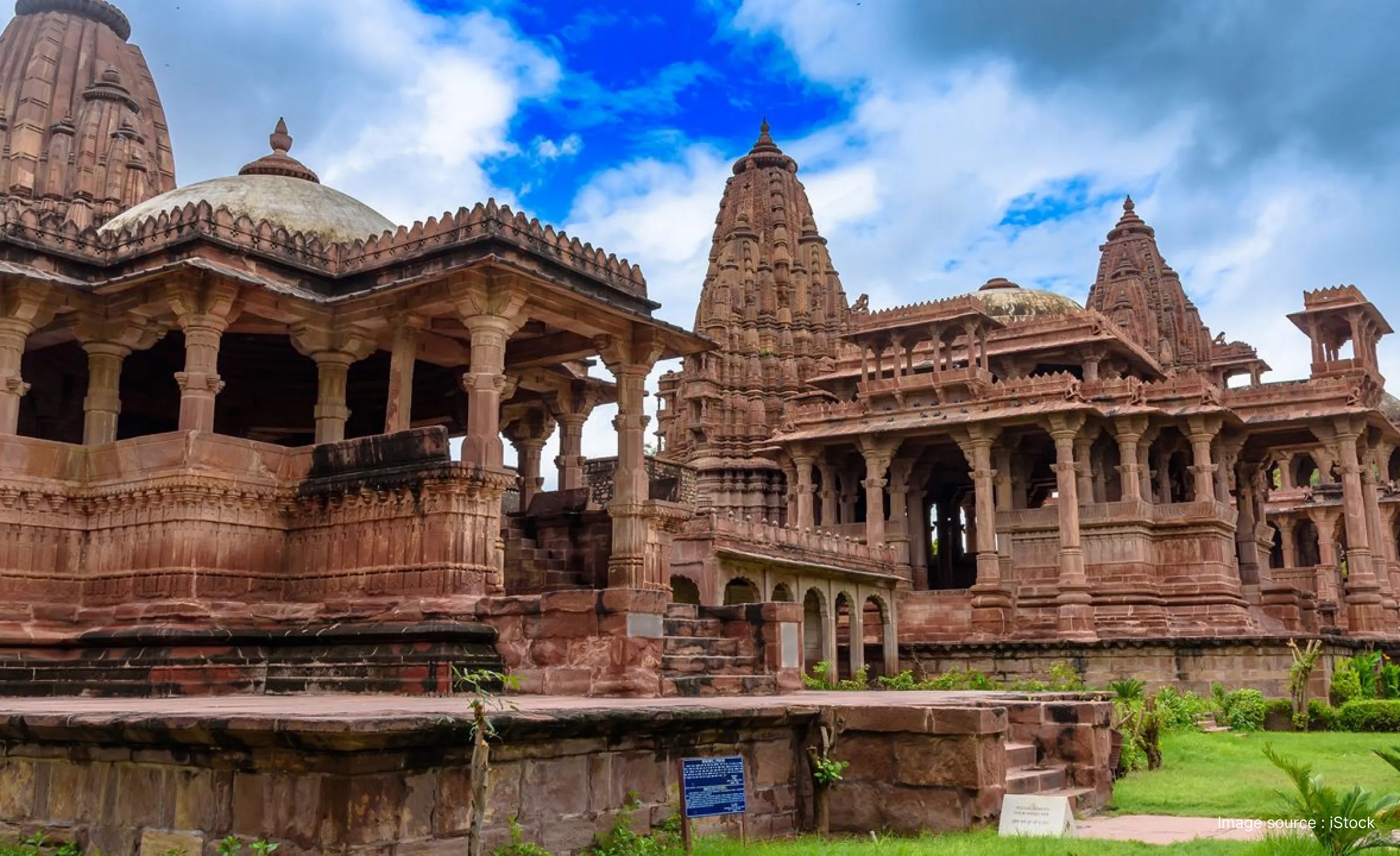 A scenic wide view of the historic red sandstone royal cenotaphs and traditional architecture at Mandore Gardens in Jodhpur.