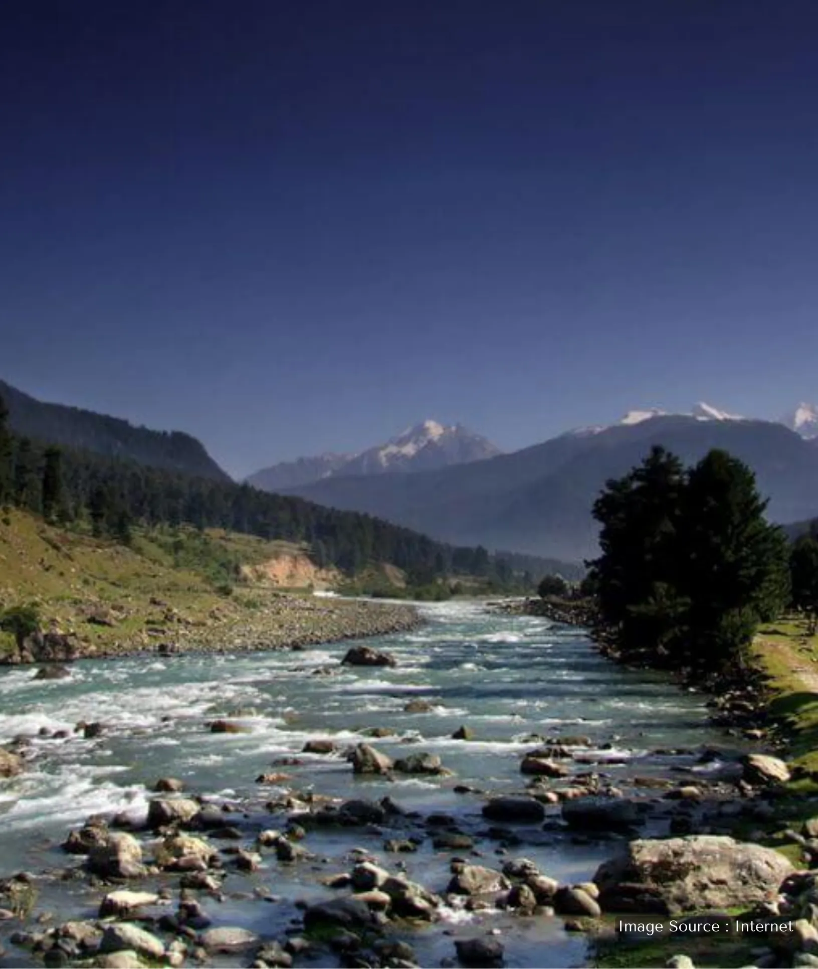 Majestic snow-capped mountain peaks at Chandanwari, Pahalgam, under a bright blue sky with light clouds.
