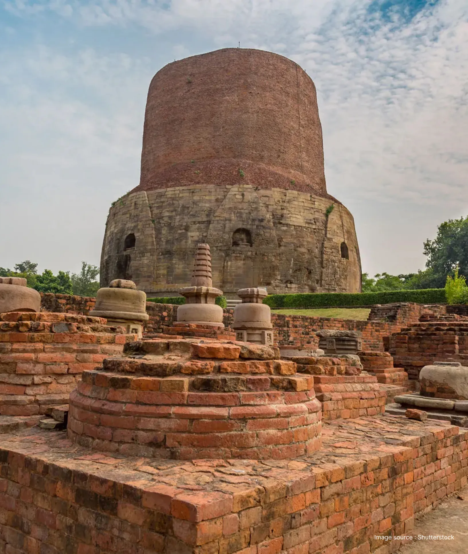 Archaeological remains of Buddhist structures in the foreground of the historic Dhamek Stupa in Sarnath, Uttar Pradesh.