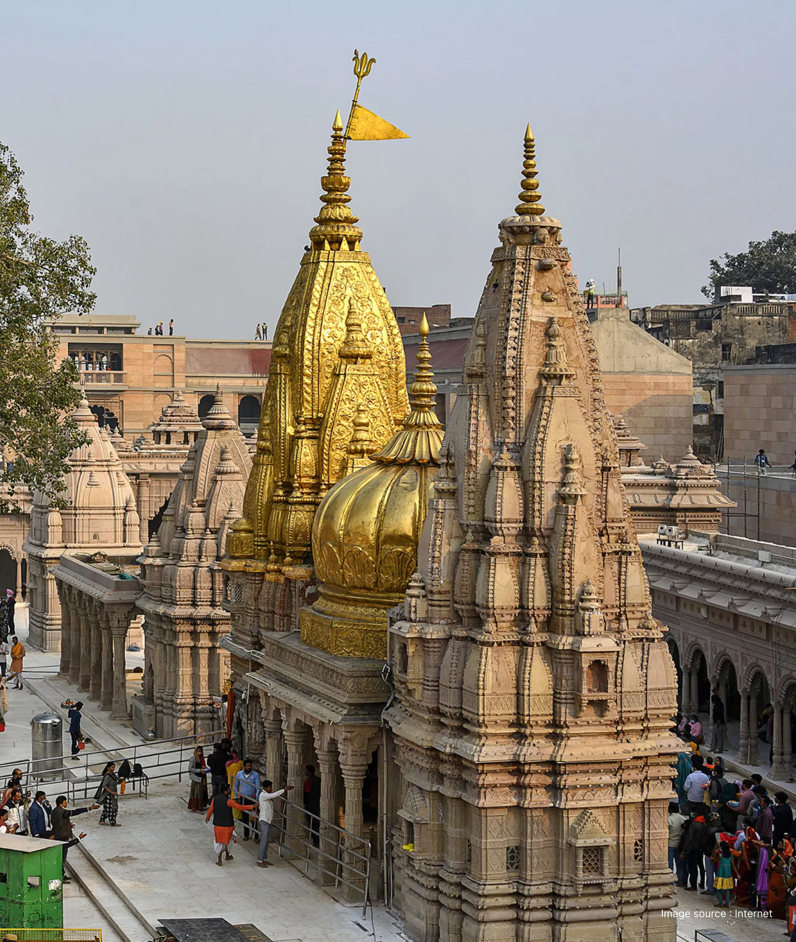 Detailed view of the golden and stone carved spires of Kashi Vishwanath Temple under a clear sky in Varanasi.