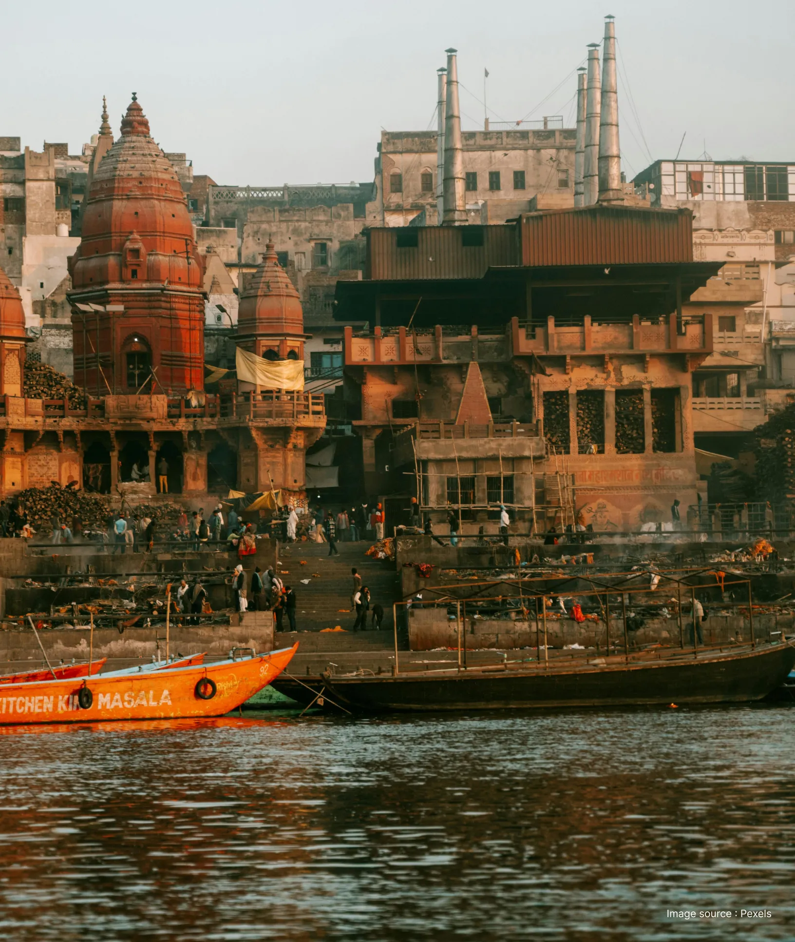 View from the Ganges River of Manikarnika Ghat in Varanasi, showing traditional cremation pyres, temples, and boats.