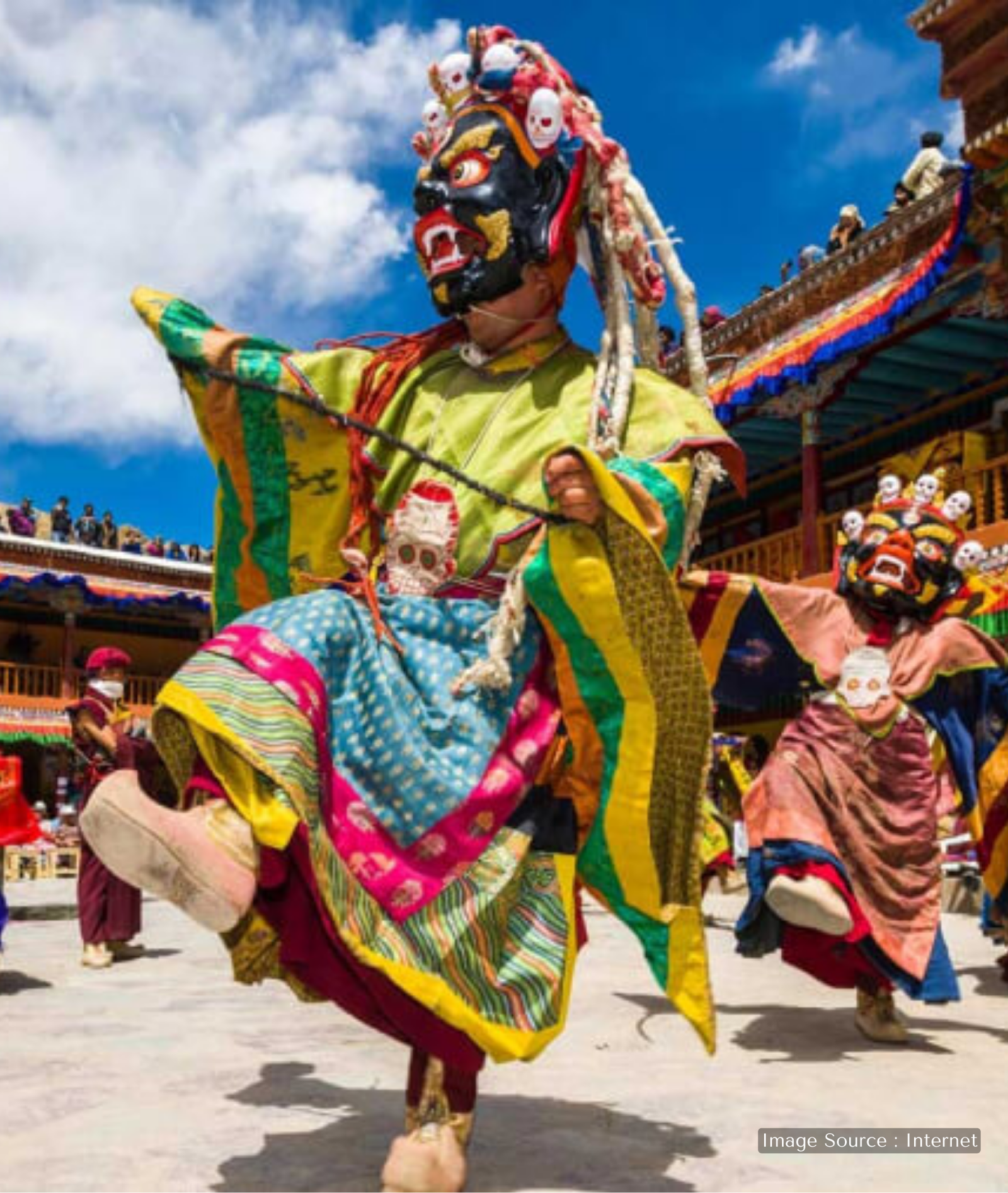 Masked monk performing traditional Cham dance during the Hemis Festival at Hemis Monastery, Ladakh, wearing vibrant ceremonial robes and a fierce deity mask against a Himalayan monastery backdrop.