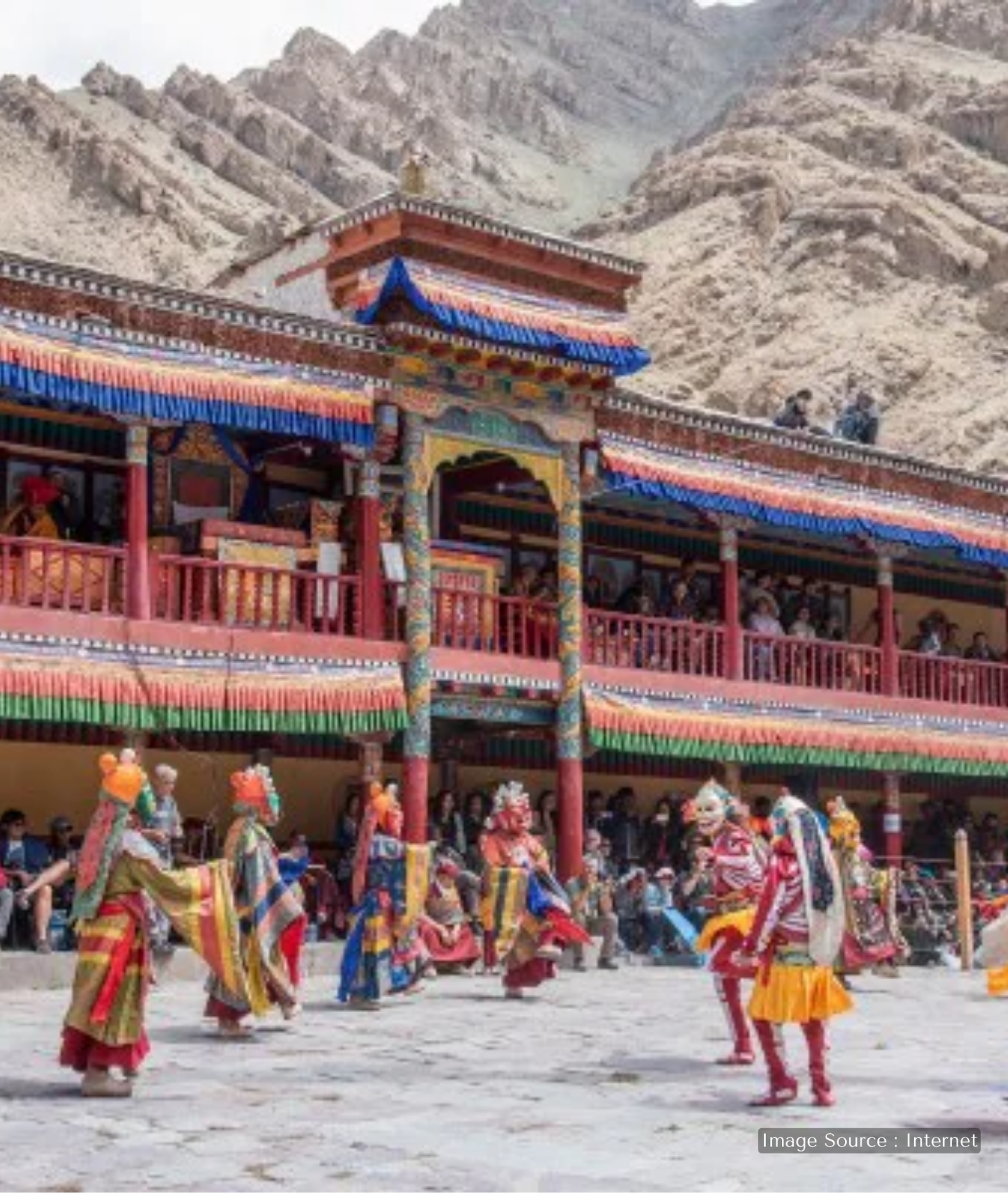 Traditional Cham masked dance performance at Hemis Monastery in Ladakh during a Buddhist festival, set against rugged Himalayan mountains
