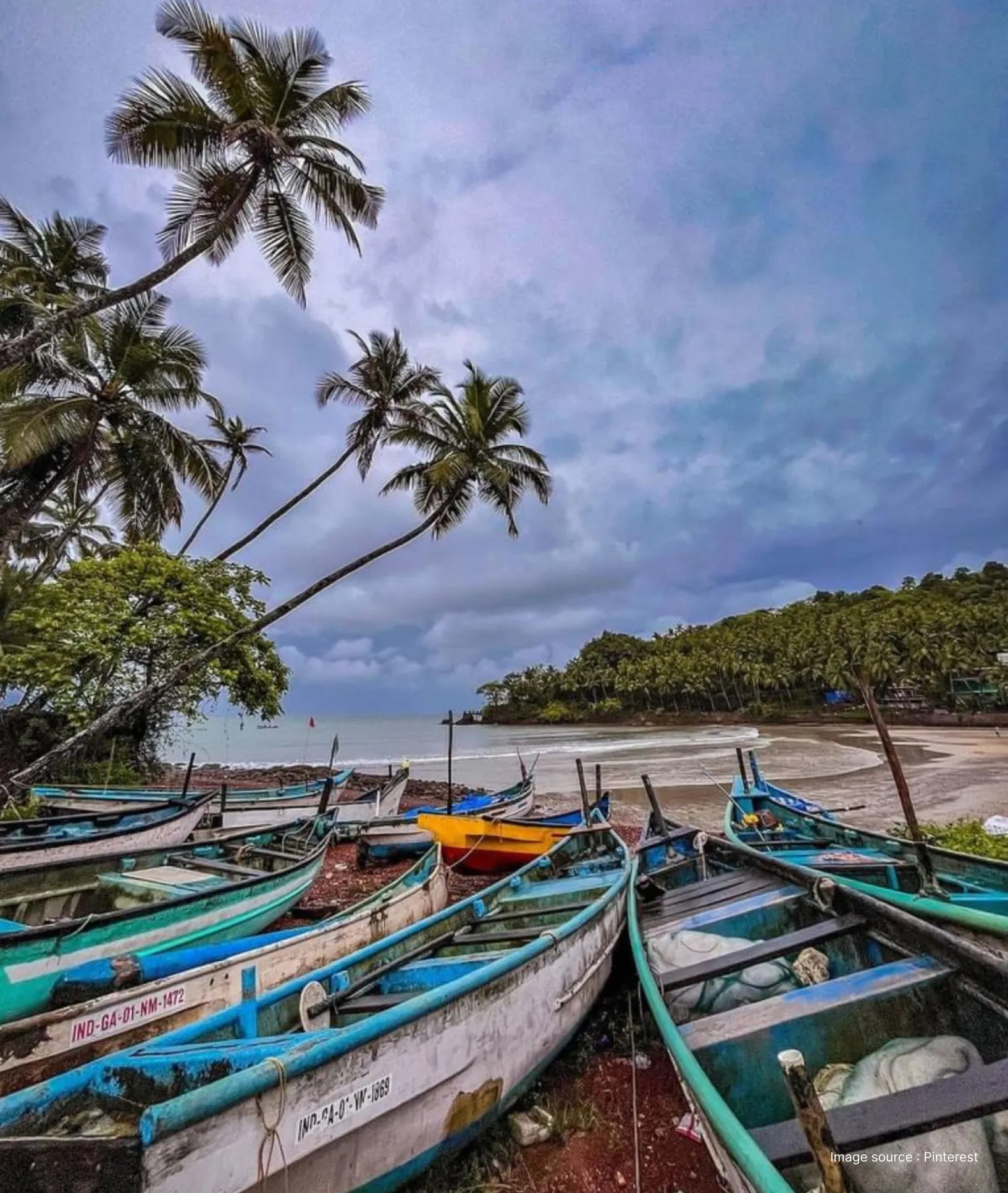 Traditional fishing boats lined up at Colva Beach in Goa with palm trees and a serene Arabian Sea backdrop