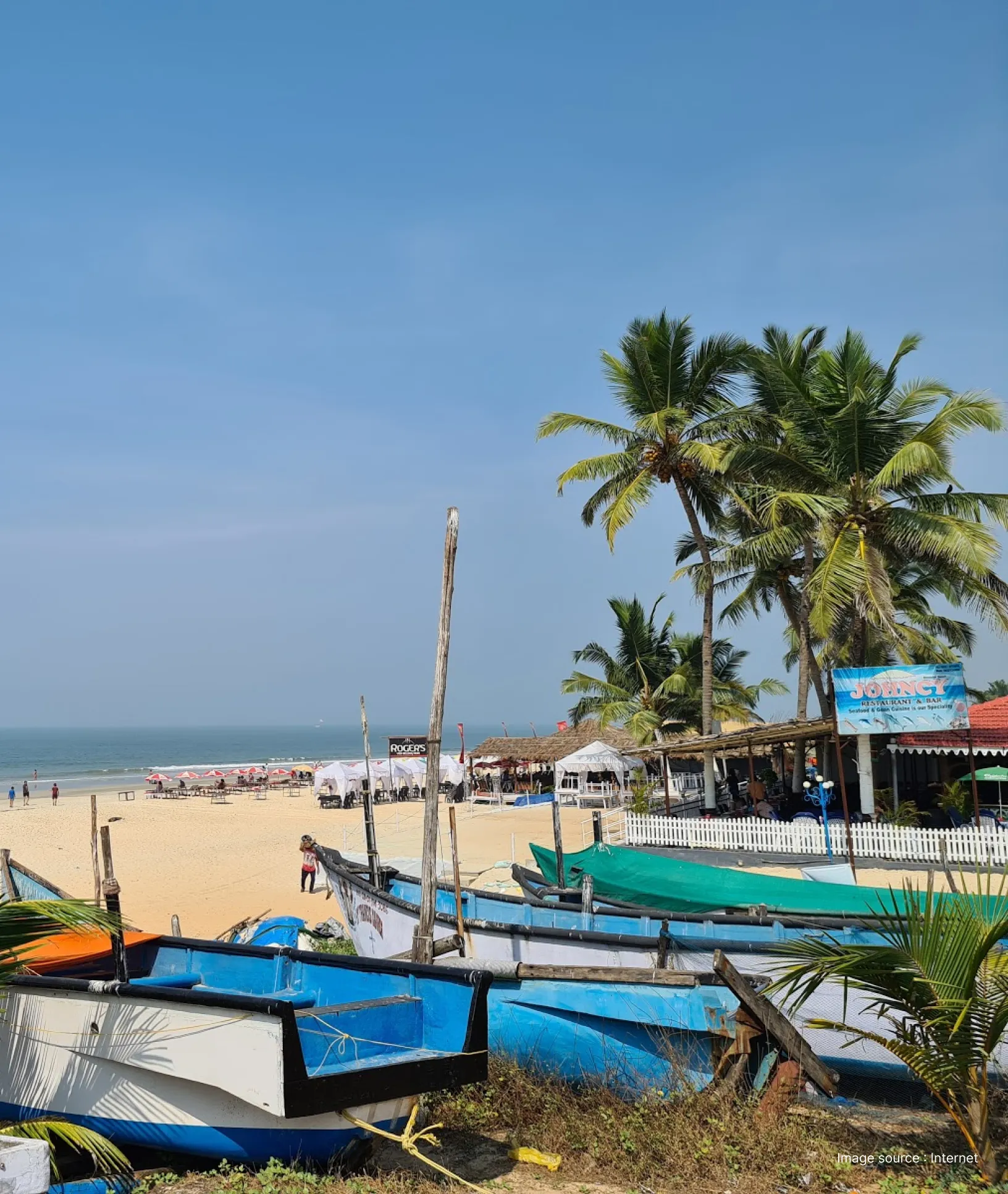 Benaulim Beach in South Goa with traditional fishing boats, palm trees, beach shacks, and a calm sandy shoreline