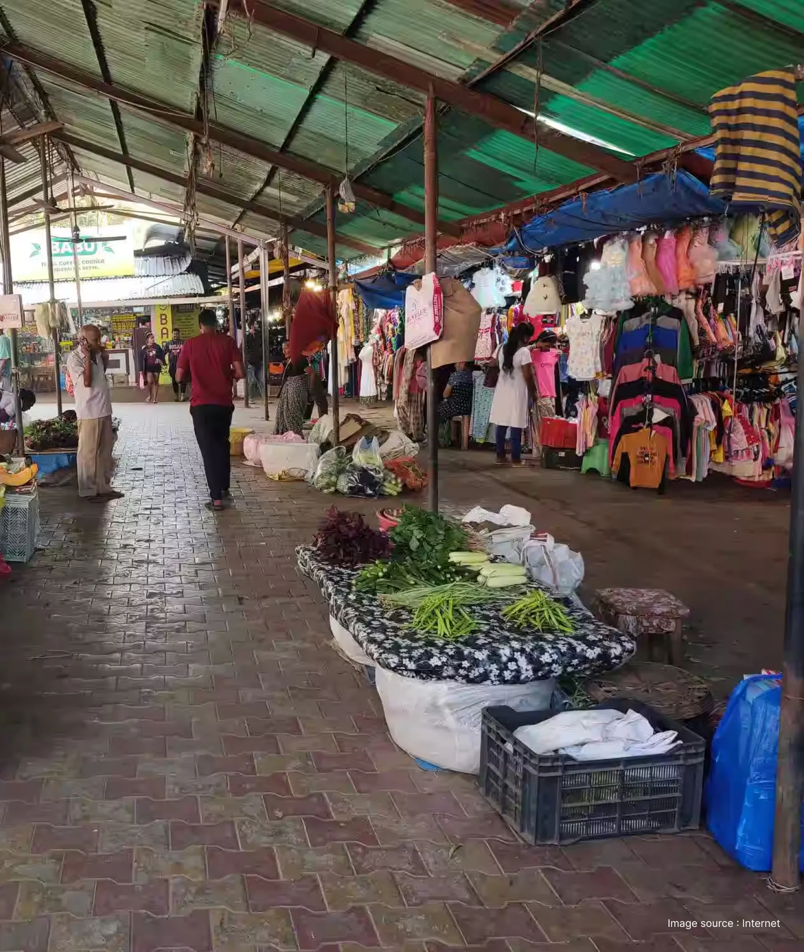 Local market in Margao, Goa showing vegetable stalls, clothing shops, and everyday shopping activity under covered walkways