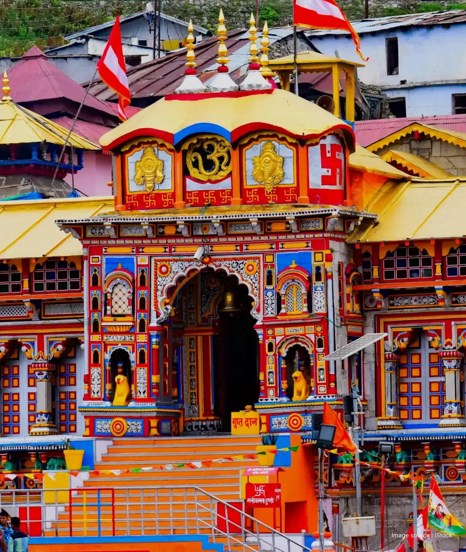 Badrinath Temple in Uttarakhand showcasing its vibrant multicolored façade, ornate entrance, and sacred Hindu symbols against the Himalayan town backdrop