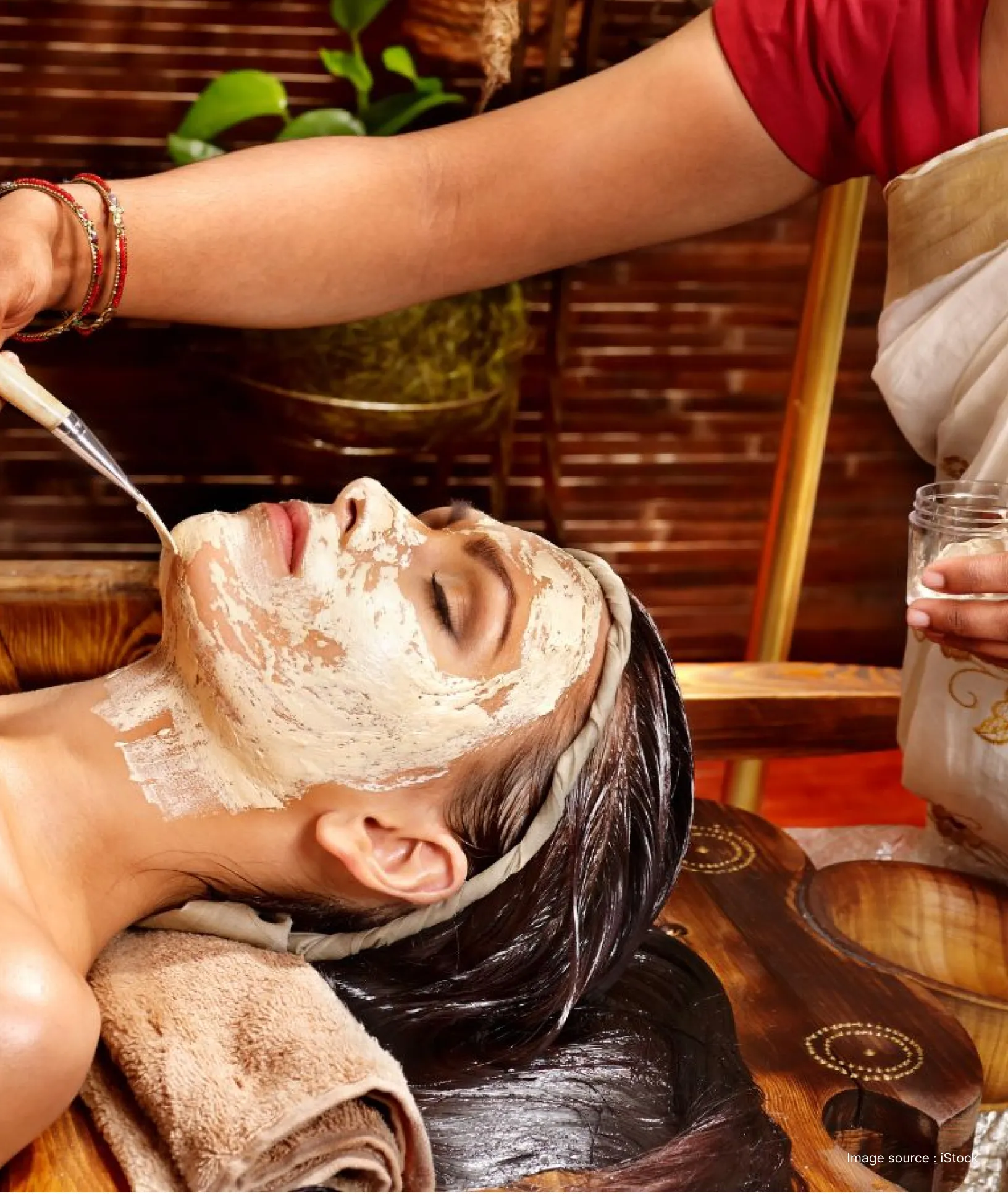 a woman applying traditional ayurvedic paste on face of another woman