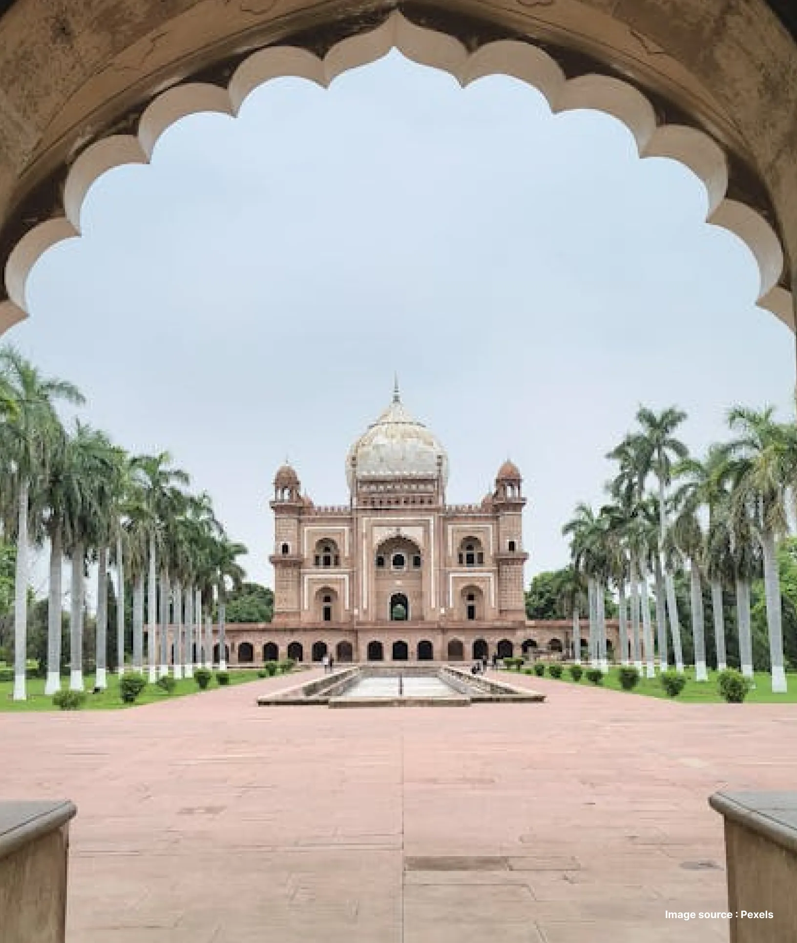 view of delhi's humayun's tomb flanked by palm trees on either side framed by an archway on a cloudy day