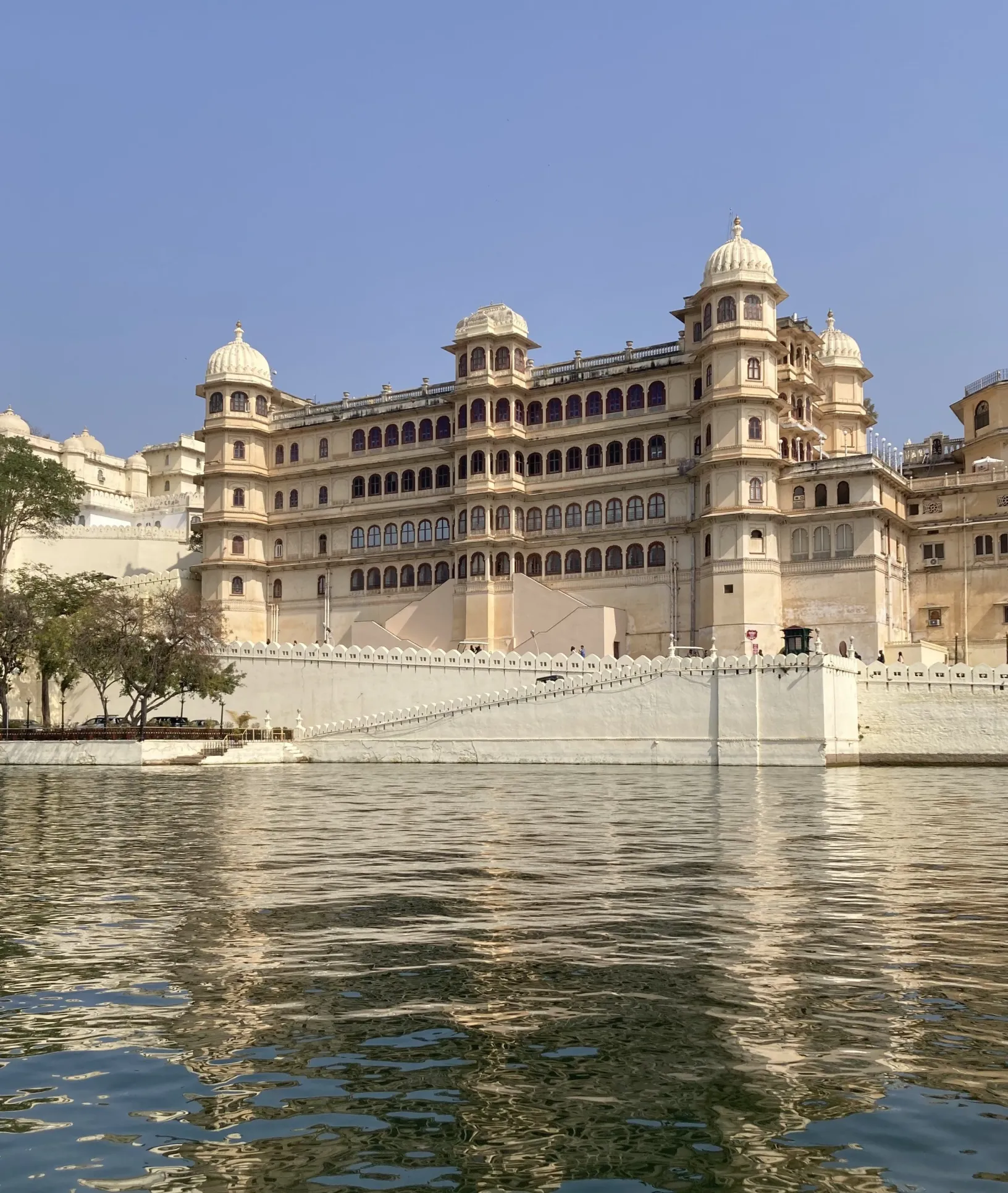 side angled view of the city palace from the lake pichola