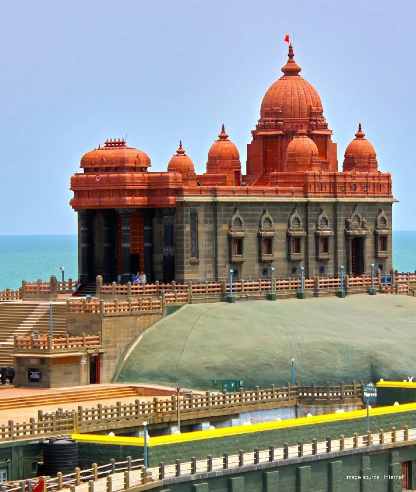 a grey building with red domes- vivekanada rock memorial at india's southernmost point, kanyakumari