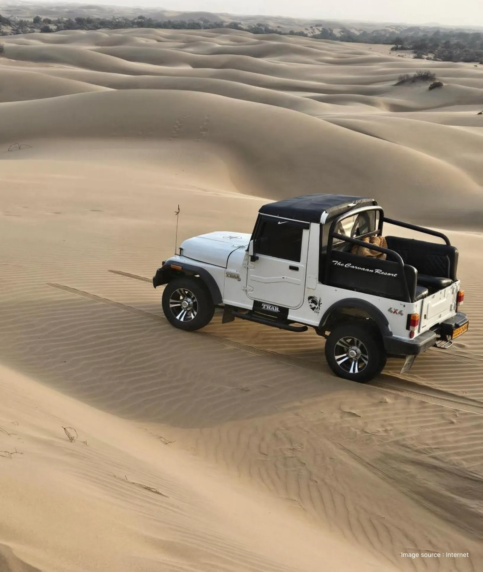 a white jeep driving through the vast expanse of the golden thar desert
