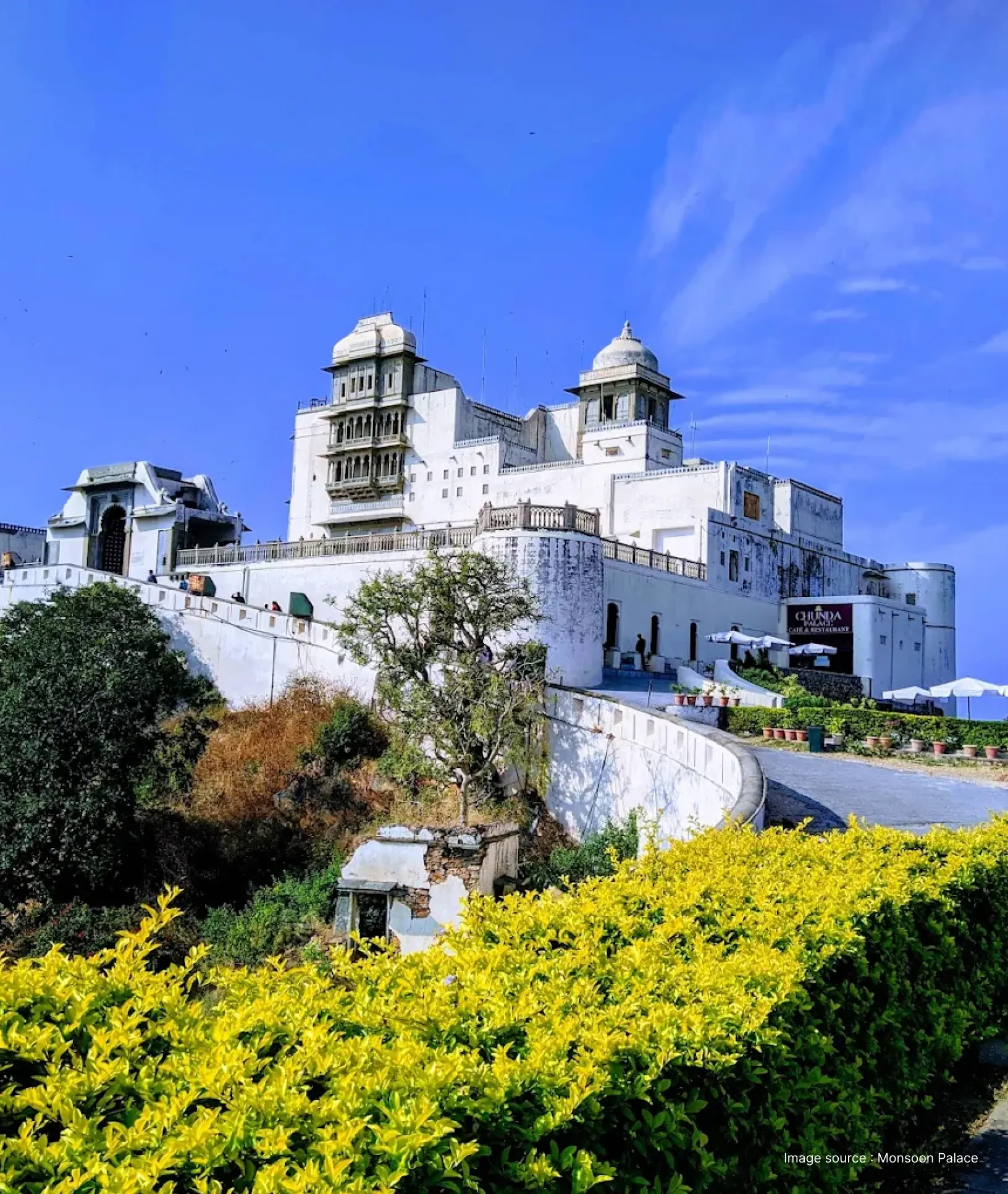 view from the hill of the white monsson palace on a clear sunny day with bushes in the front