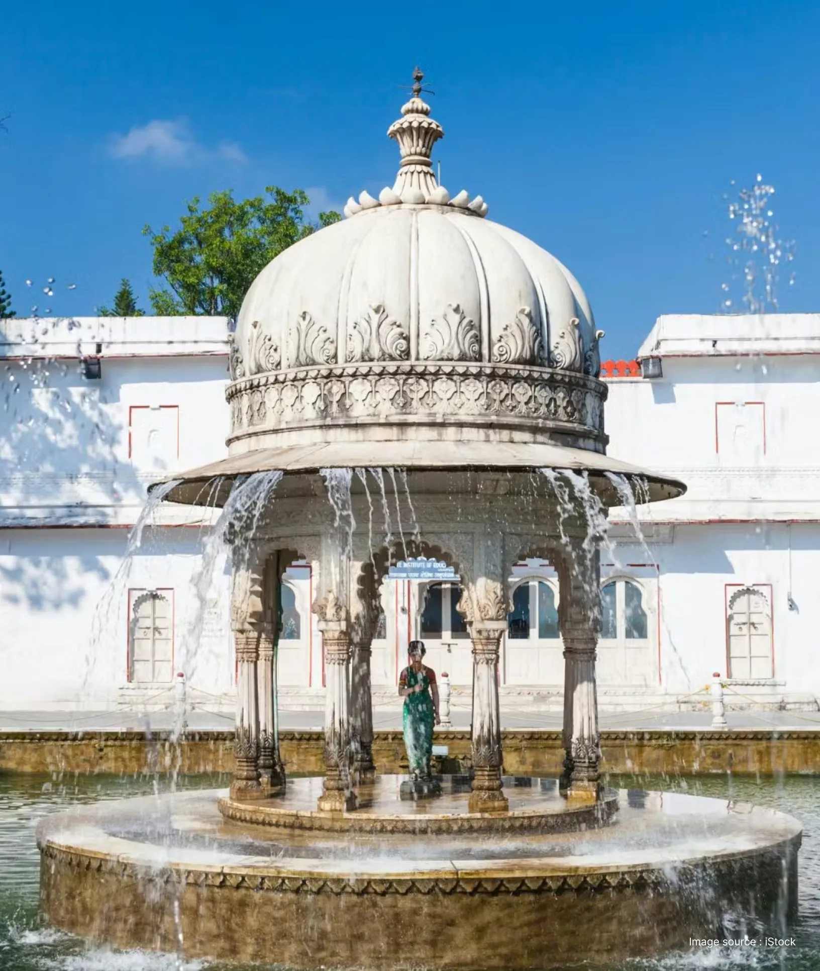 white cenotaph structure with detailed carvings in midst of a pond at saheliyon ki bari