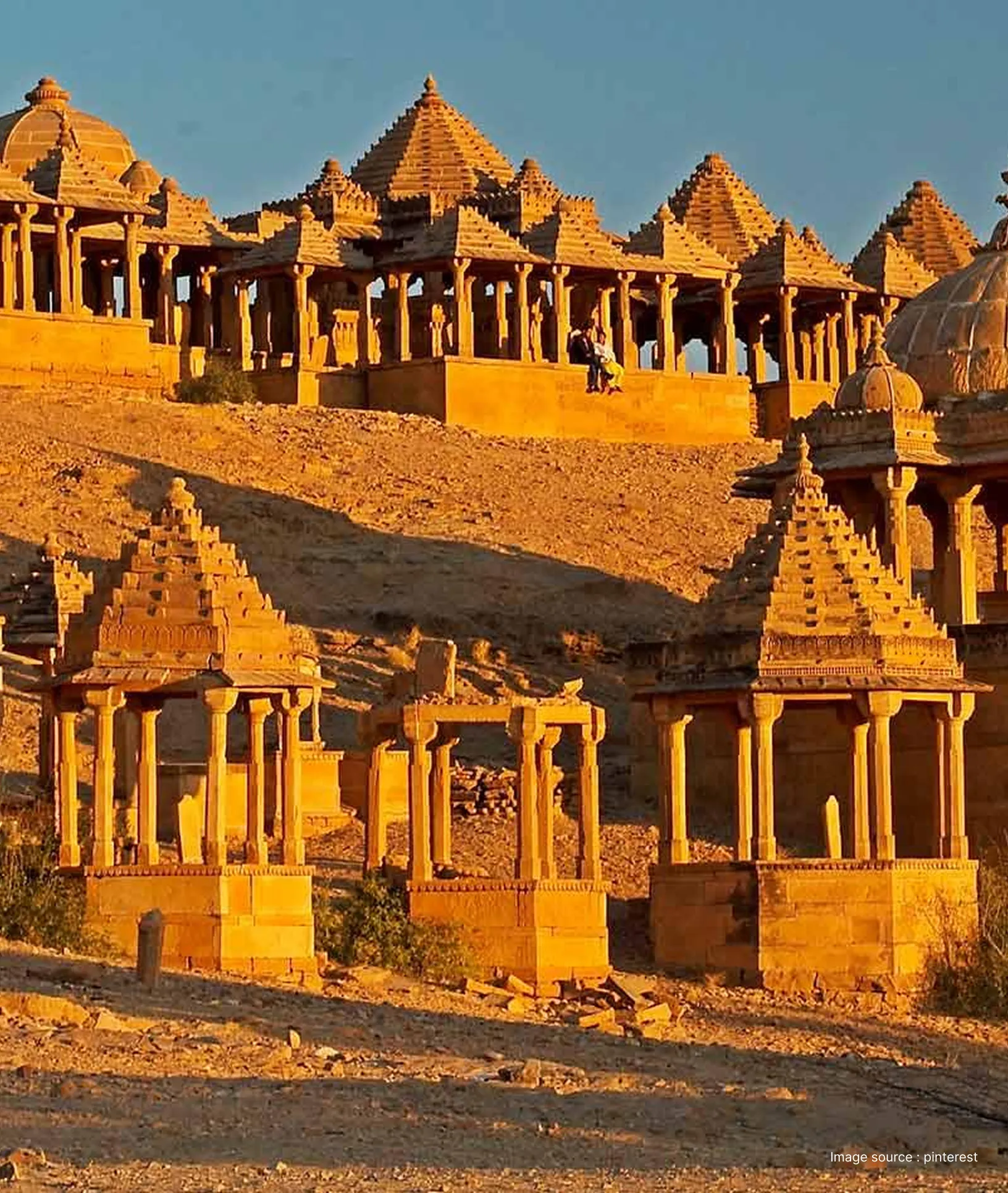 golden sandstone cenotaphs in a desert, blending into the golden landscape in the sun
