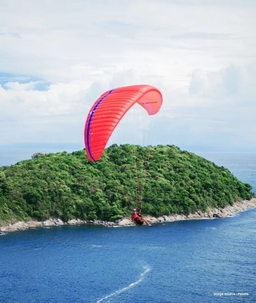 an aerial shot of parasailing with an orange parachute over andaman