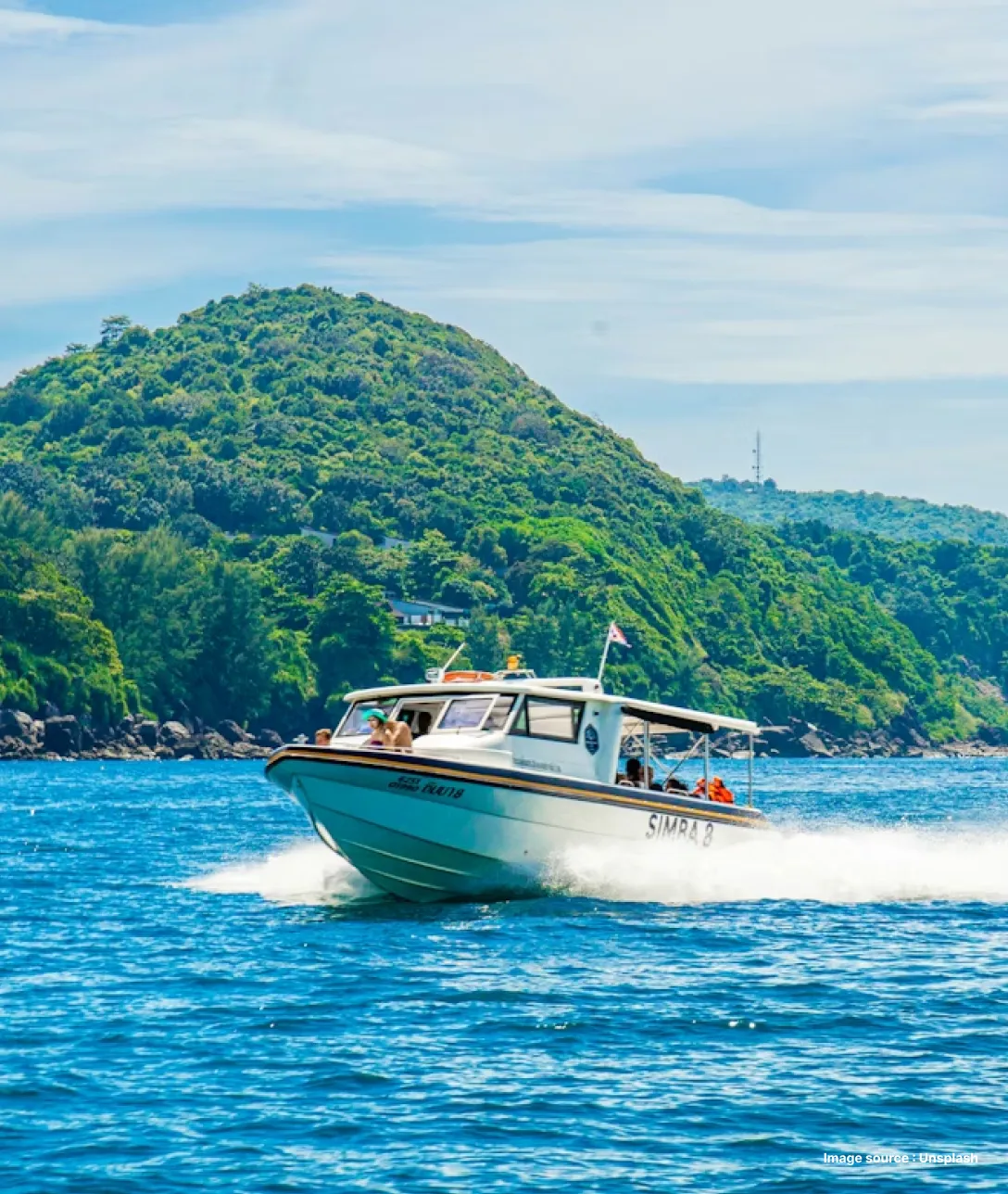a yacht speeding thrugh blue waters with green lush hill in the backdrop