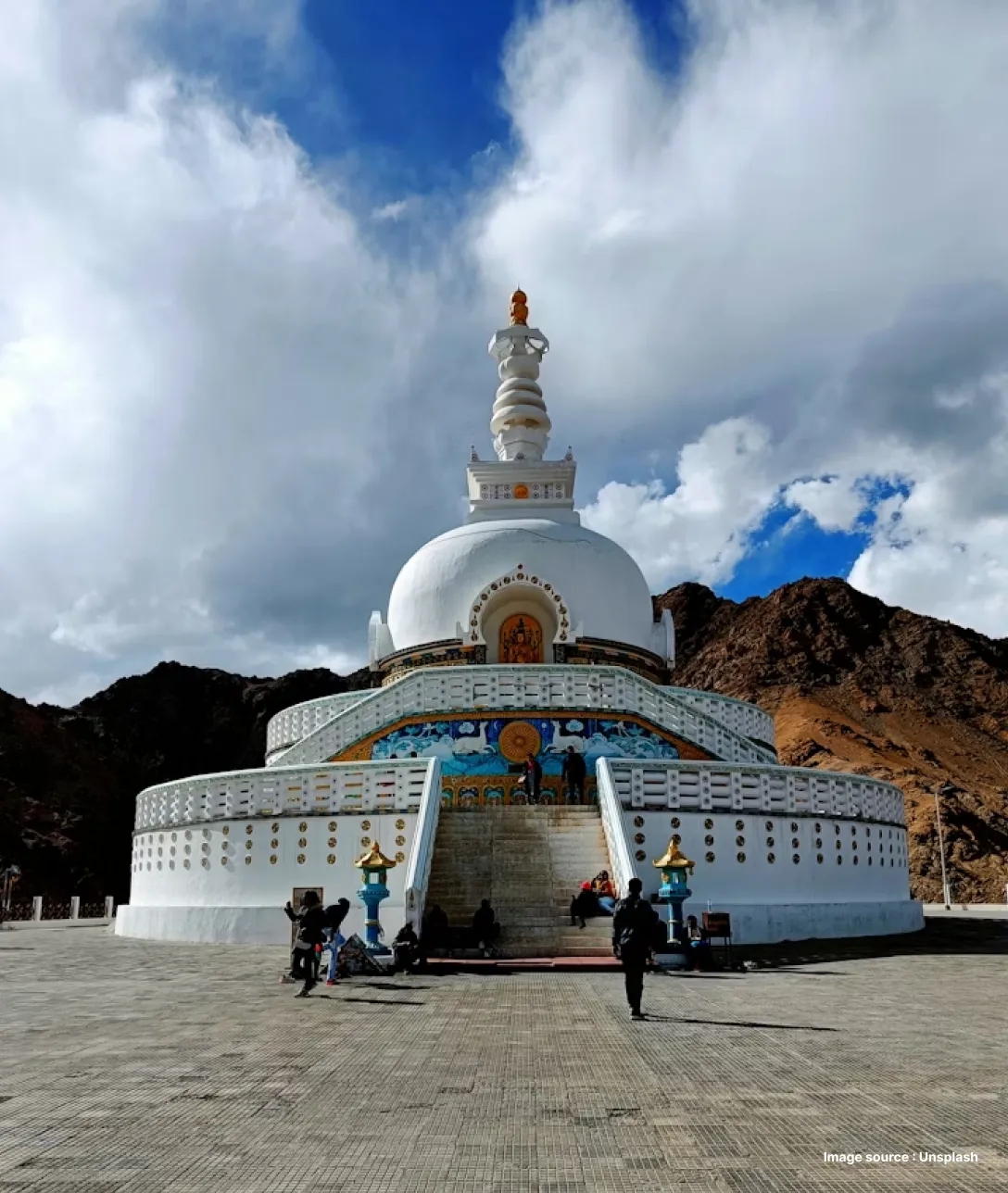 a dome shaped white structure with golden accents surrounded by hills