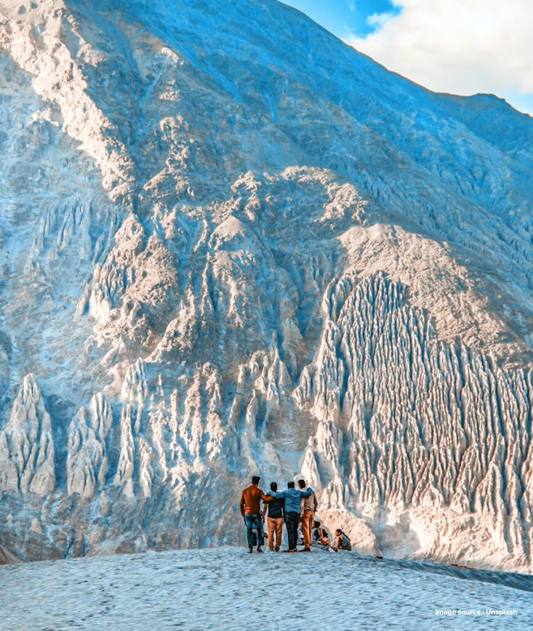 a group of tourists pose in front of a huge snow capped peak