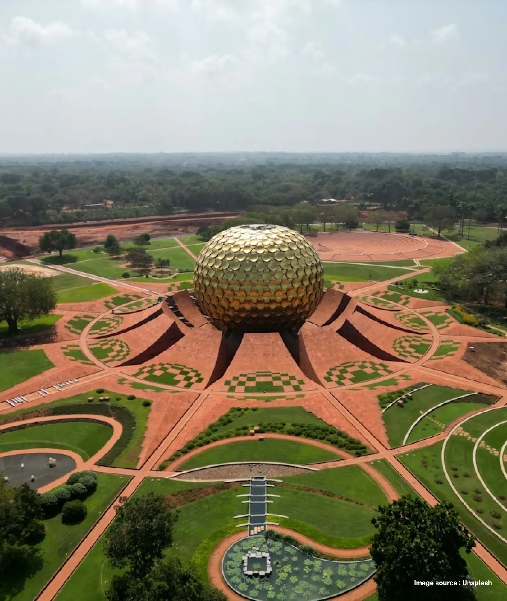 aerial shot of auroville's golden domed matrimandir with gardens extending from all sides