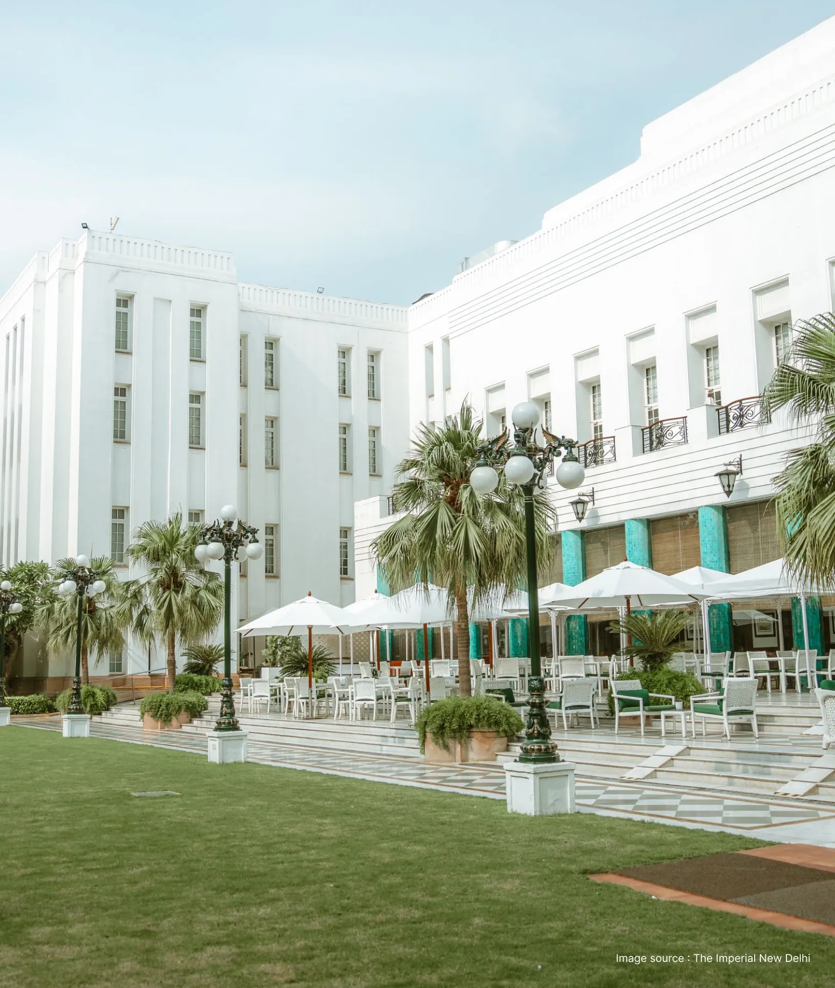 garden side view of the imperial's white building architecture in new delhi with trees & seating area