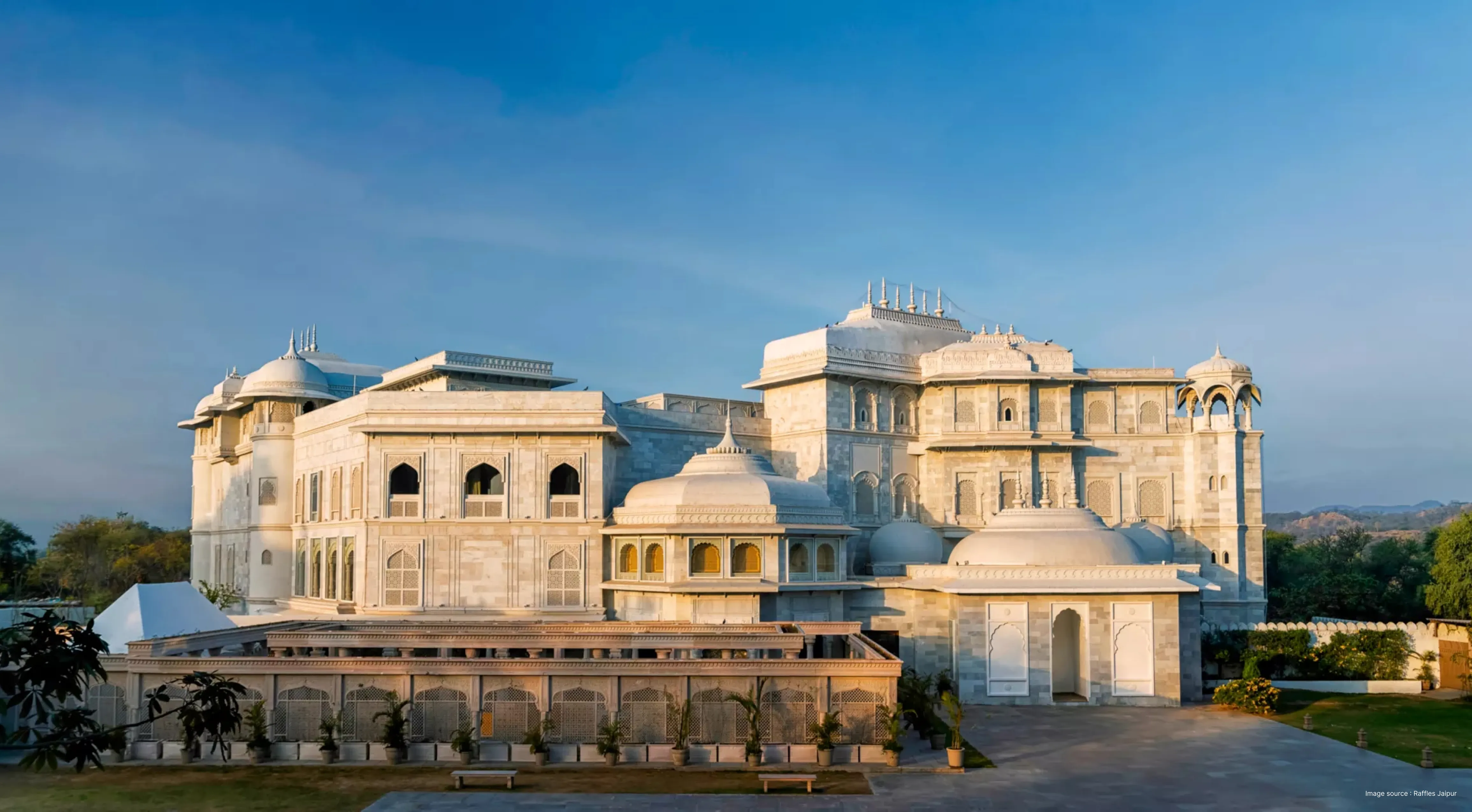 the grand white building of raffles jaipur in sunlight with opulent domes