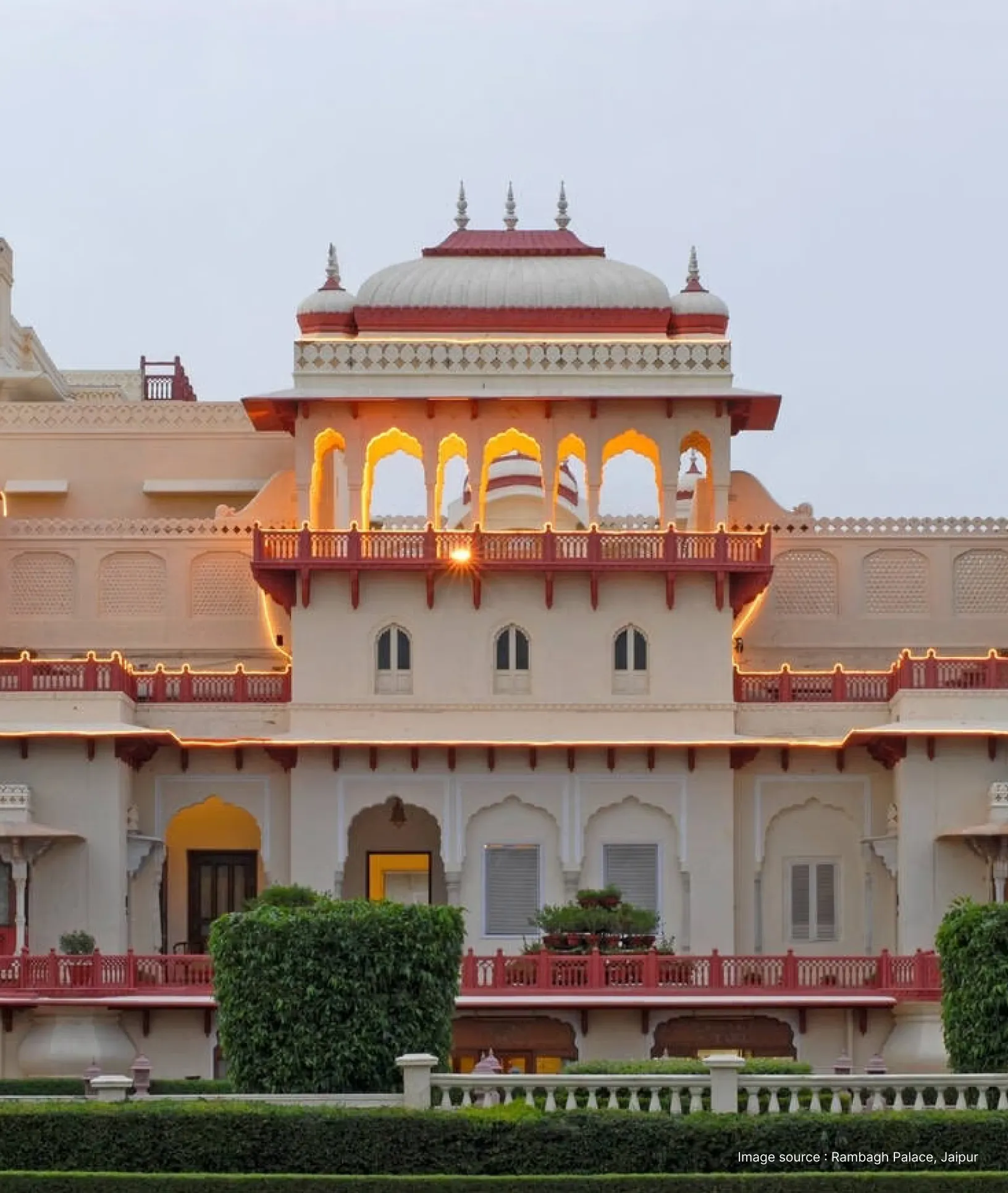 lit up dome with red accents of the taj rambagh palace in jaipur at dusk