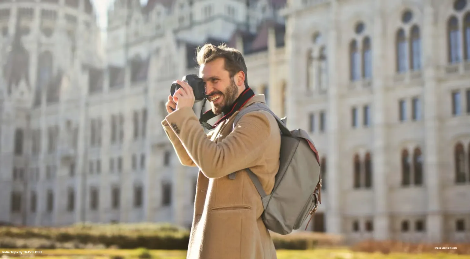 A picture of a man taking a photograph whilst smiling during the day time