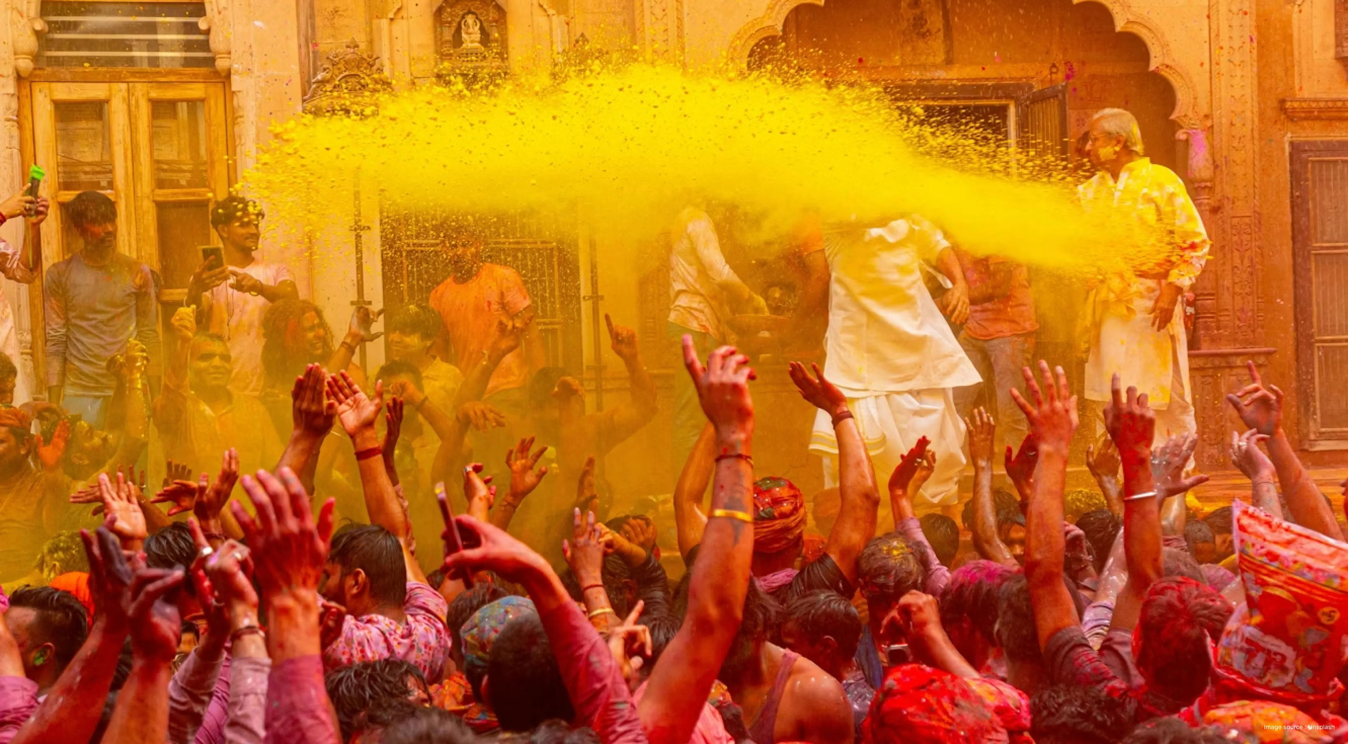 beautiful shot of people celebrating holi with colors thrown in the air