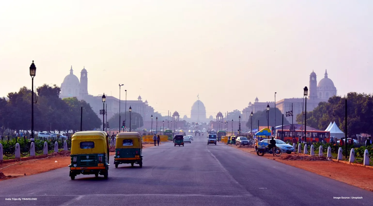 A picture of a road in India, with auto-rickshaws and cars on them during the crack of dawn.