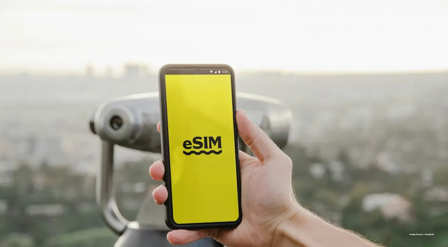 a person holding up a phone with a yellow screen that reads eSIM