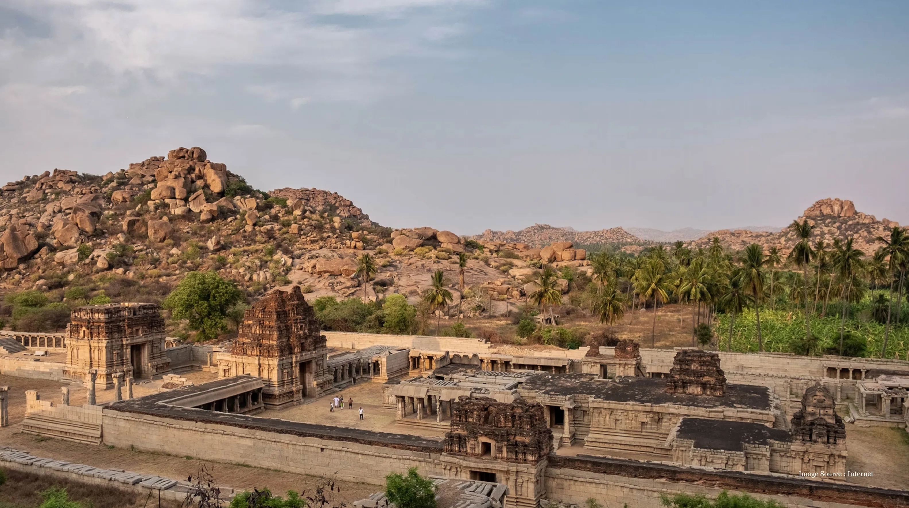 Ancient temple ruins surrounded by rocky hills and palm trees, showcasing the serene beauty and historic charm often explored on a Cambodia holiday.