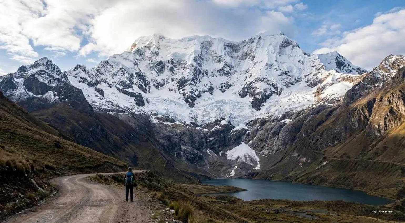snow capped peaks of the aconcagua mountain with a small lake and roads leading up to it
