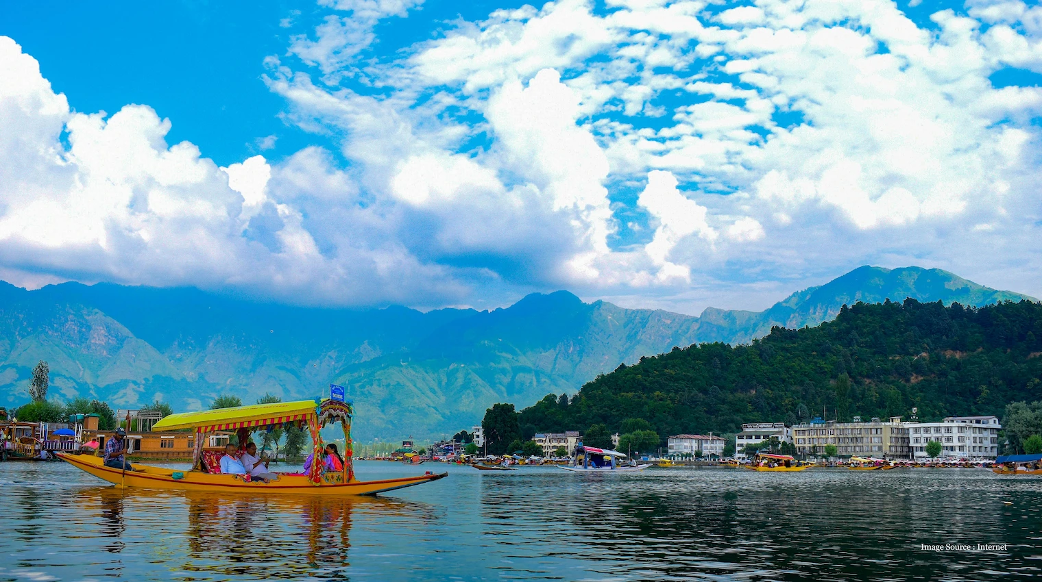 Best places to travel in India with scenic view of Dal Lake, shikara, and Himalayas in Kashmir