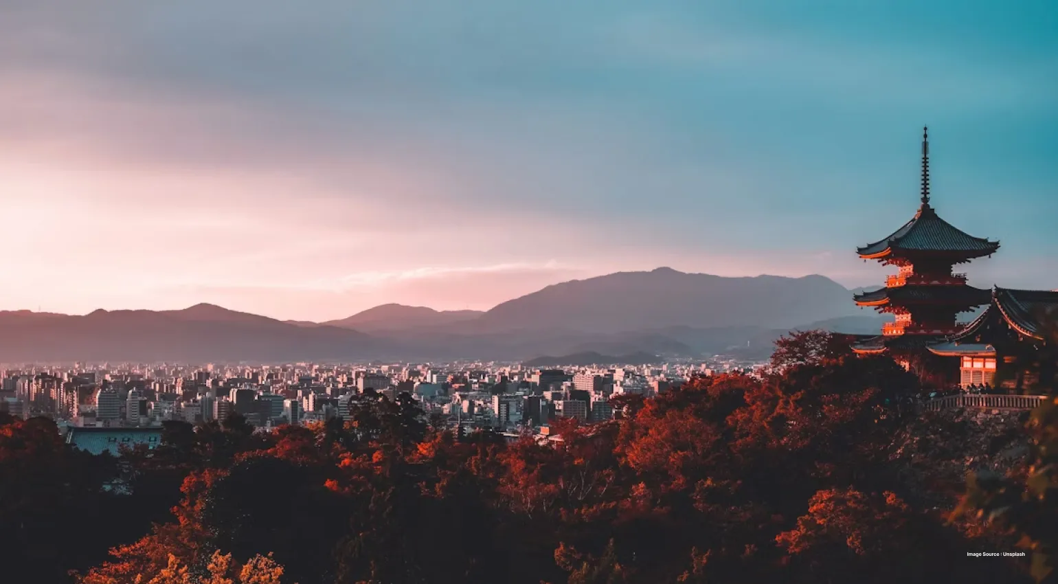 a beautiful sunset view of kyoto in japan with an area with trees and a traditional japanese temple tower in view