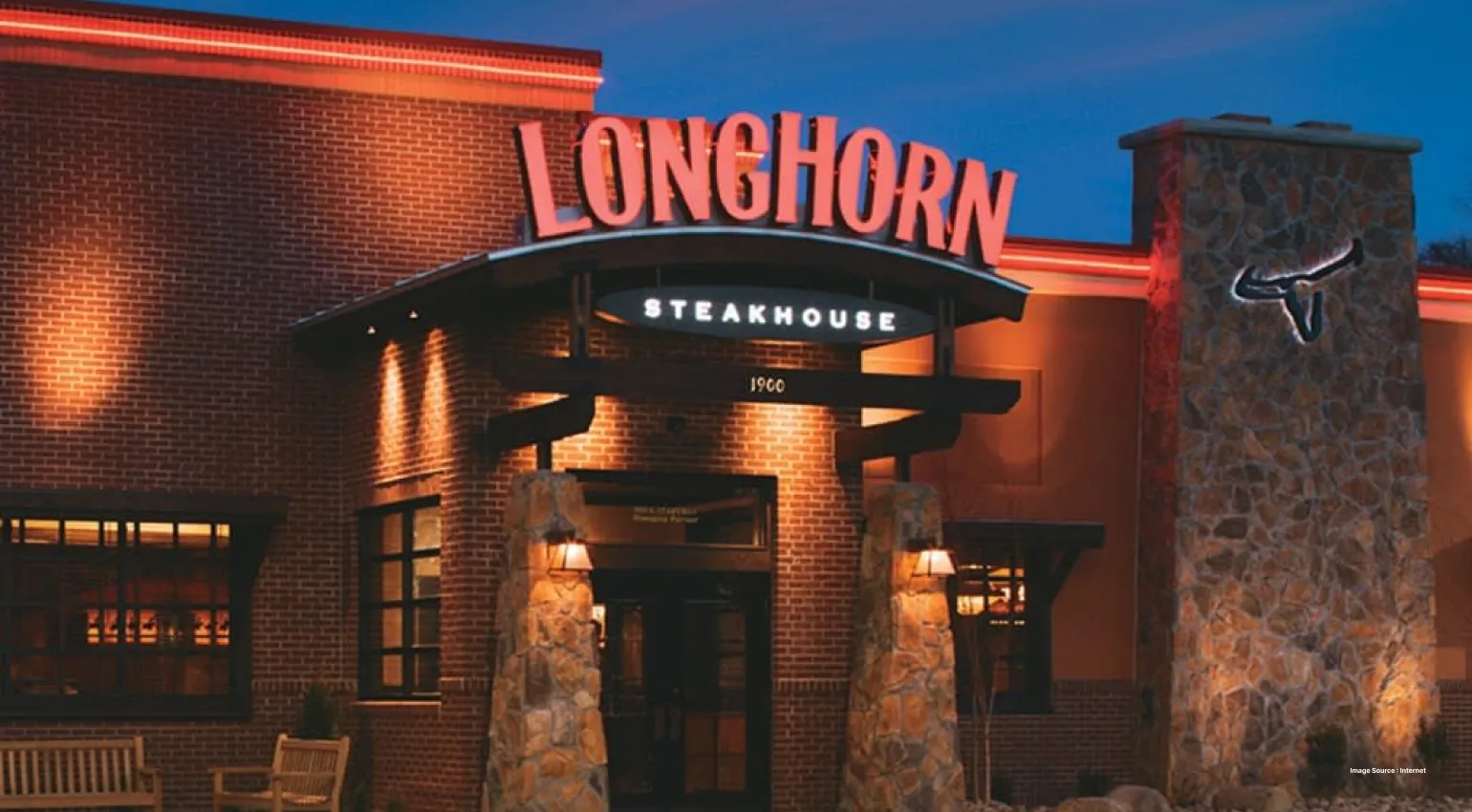 Entrance of a longhorn steakhouse restaurant lit up, sign board at dusk