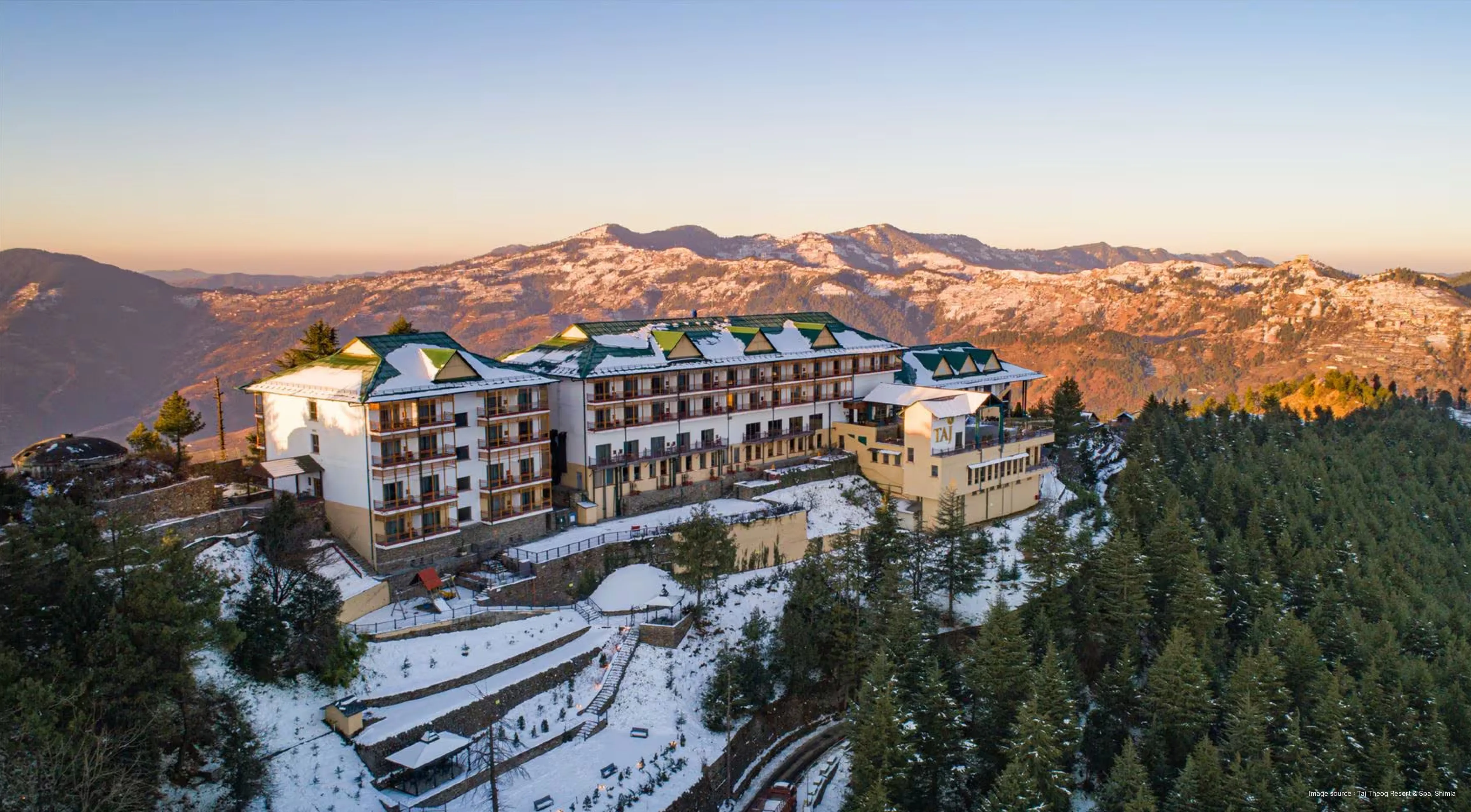 an aerial view of the Taj Theog resort, sitting on a hilltop with mountain views in the background