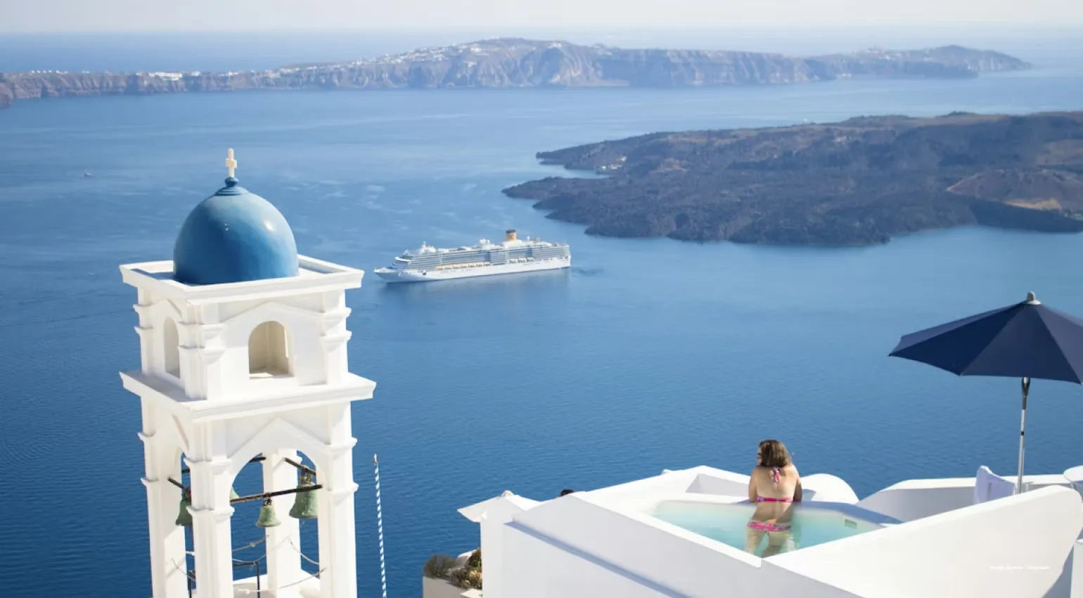 aerial shot of the santorini islands as a lady enjoys in the pool