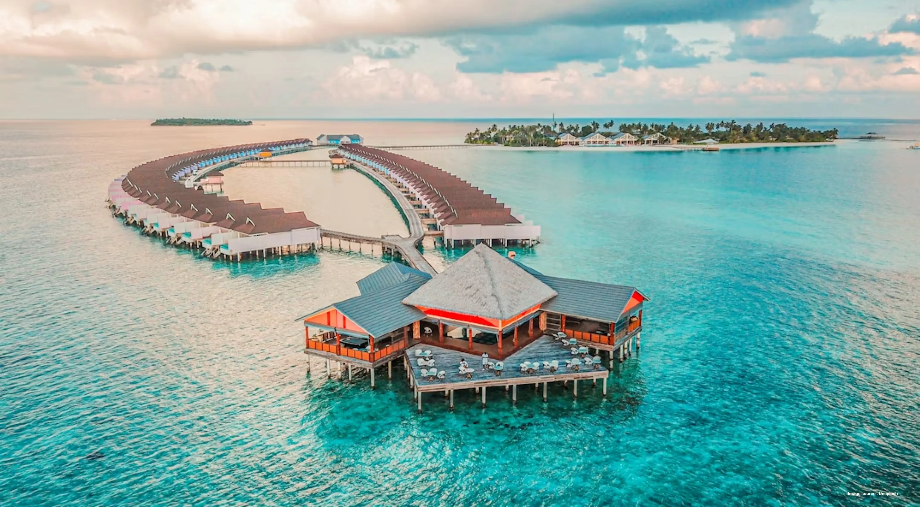an overwater resort with bungalow stays in maldives on turquoise waters on a sunny day