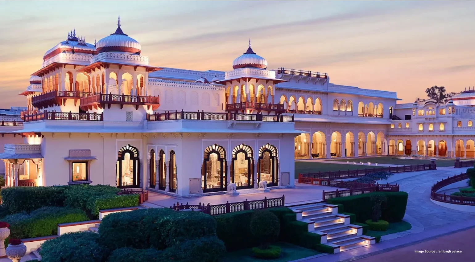 Grand palace-style heritage hotel exterior with illuminated arches at sunset