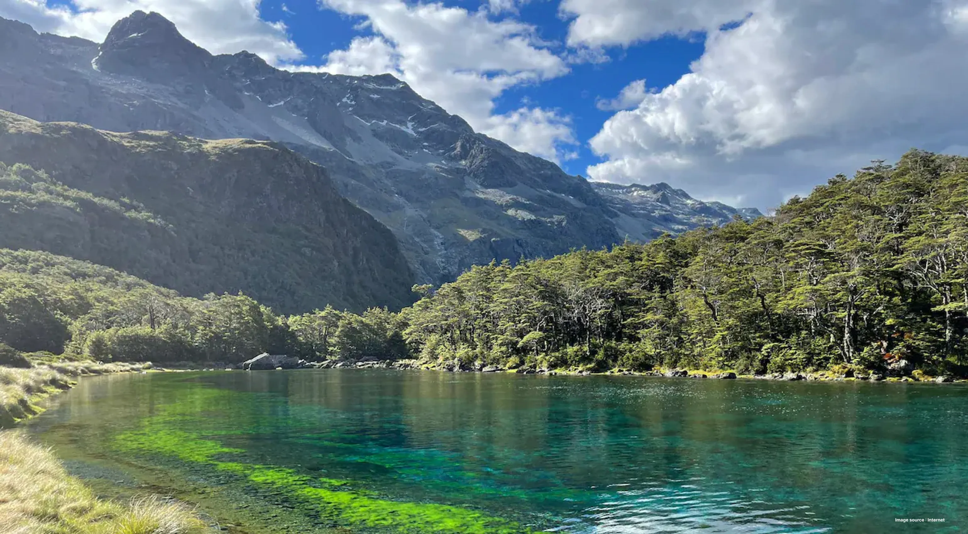 a beautiful shot of the rotomairewhenua lake with clear blue waters surrounded by green hills