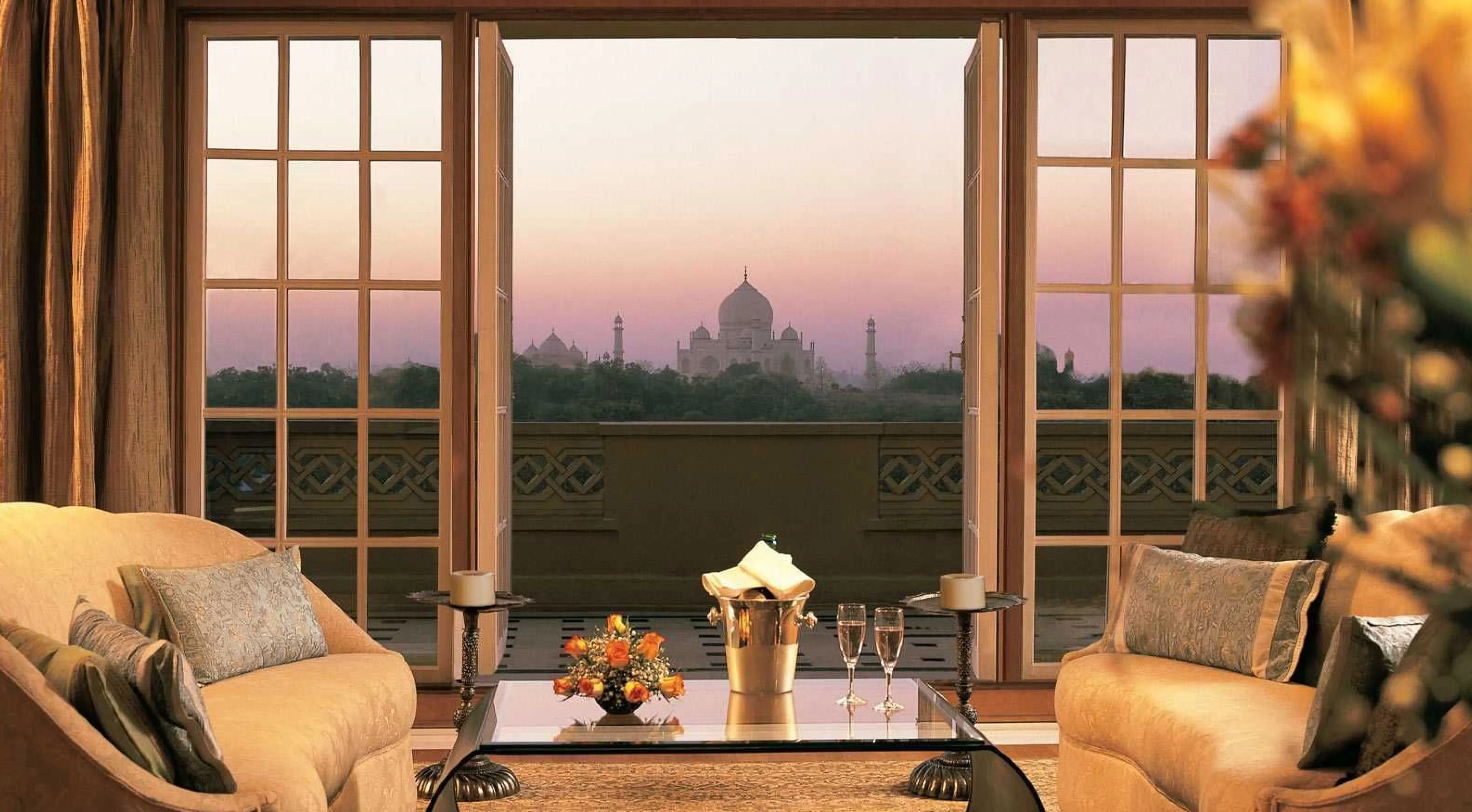 a premier suite of the oberoi amarvilas overlooking the taj mahal at sunset with pink hues inthe sky