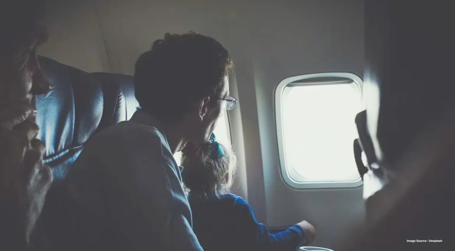 Family looking out of an airplane window during a flight, capturing the excitement of air travel and journey.