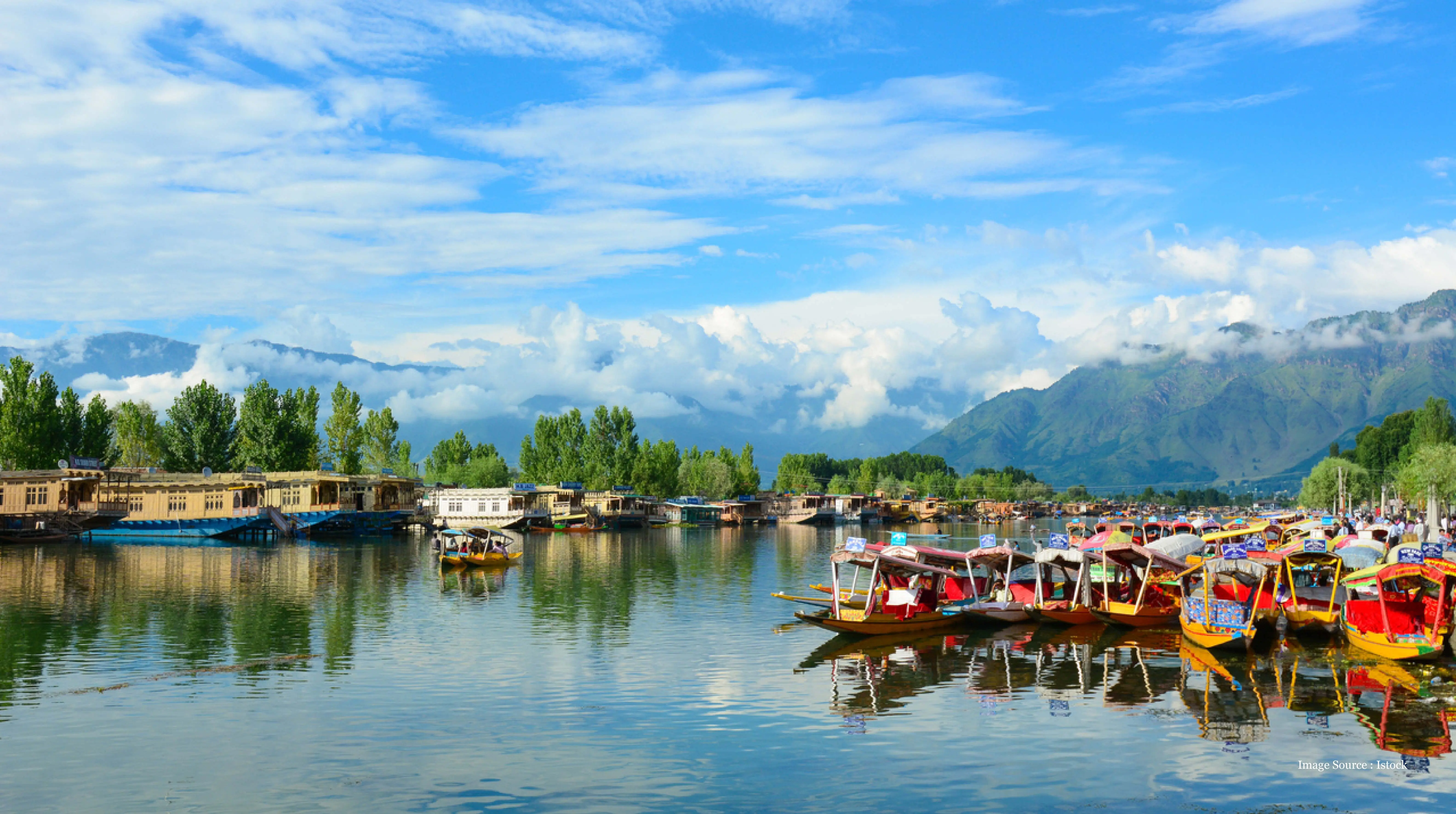 places-to-travel-in-india: Colorful shikaras on Dal Lake with mountain backdrop in Srinagar, India.