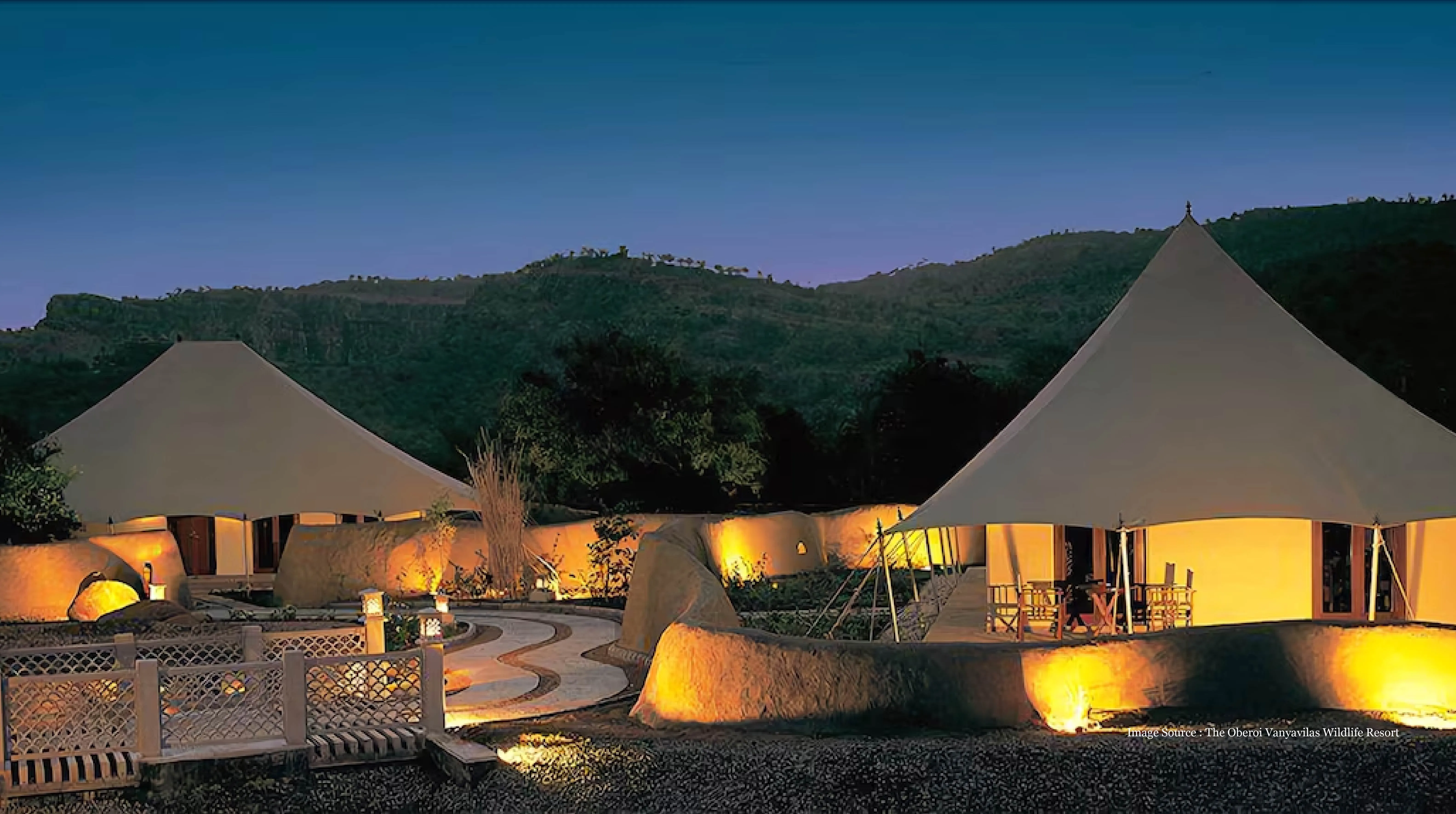 traveller tours luxury tented resort at dusk with mountain backdrop and warm lights
