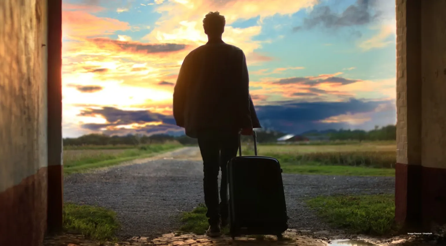 a gorgeous shot of the back of a tourist with a suitcase walking ahead into a beautiful sunset landscape