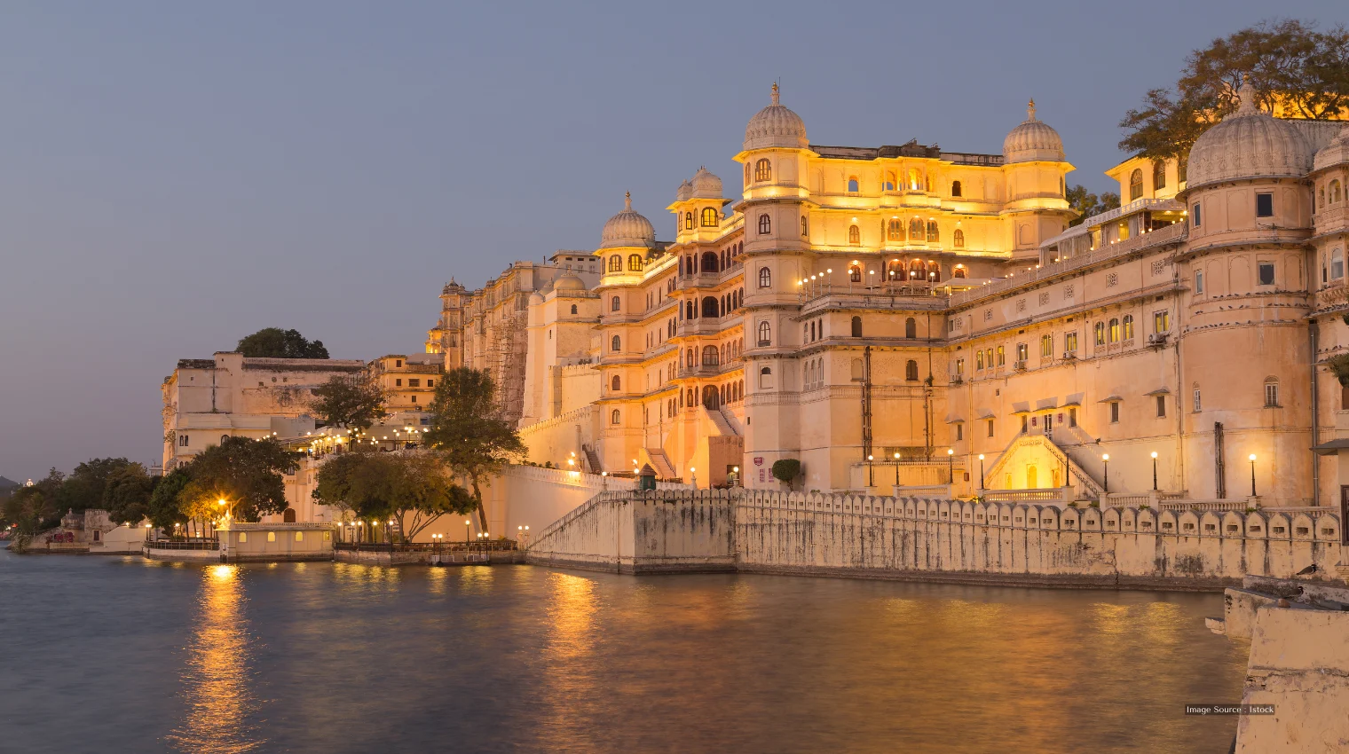 Luxury hotels in Udaipur: Stunning lakeside palace view with elegant night lighting, royal architecture, serene ambiance